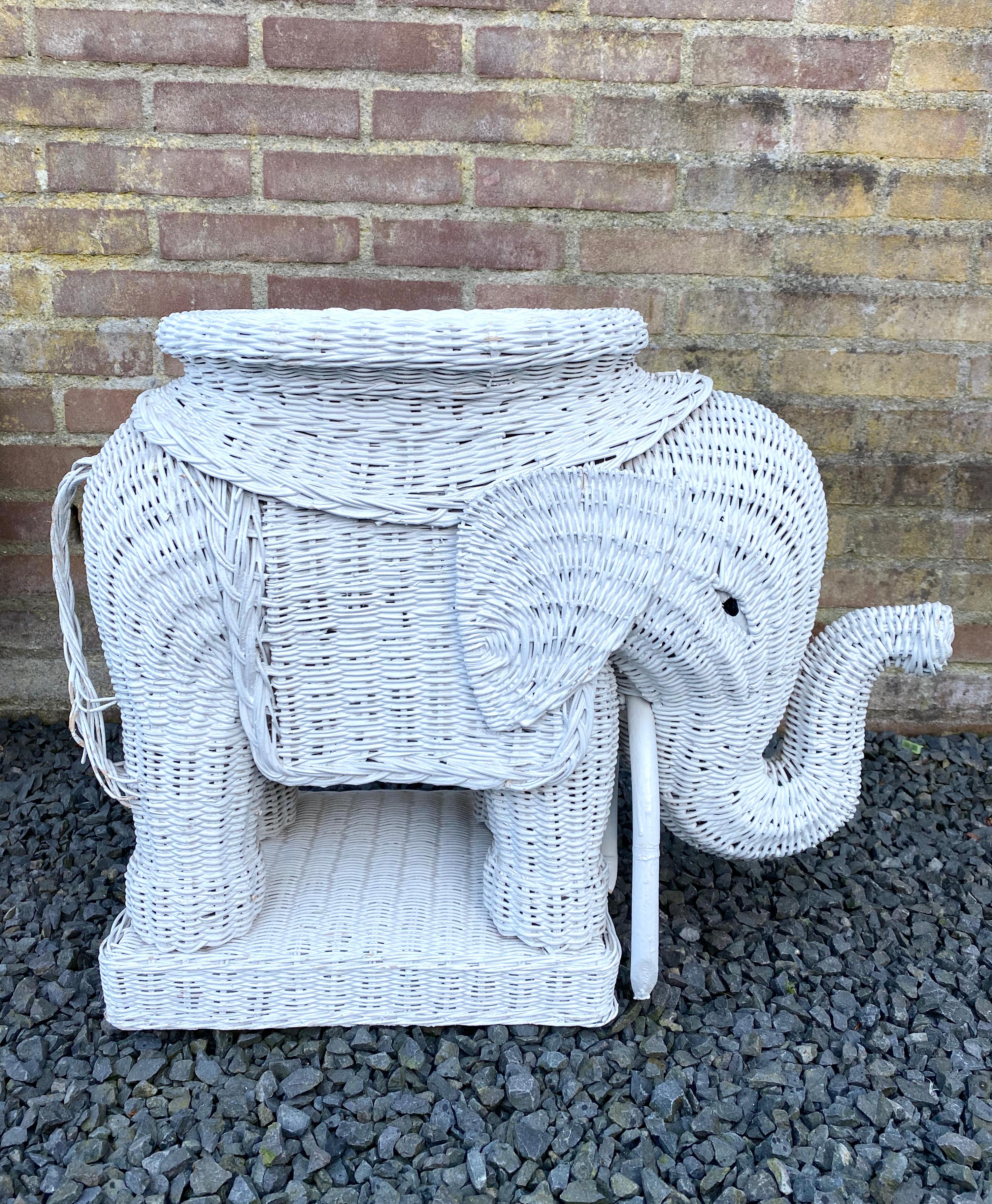 Elefante de mimbre tejido lacado en blanco que puede utilizarse para varios fines, por ejemplo, taburete de jardín, mesa auxiliar o soporte para plantas. Estilo bohemio. Esta pieza se conserva en buen estado, con algunas pérdidas de pintura en la