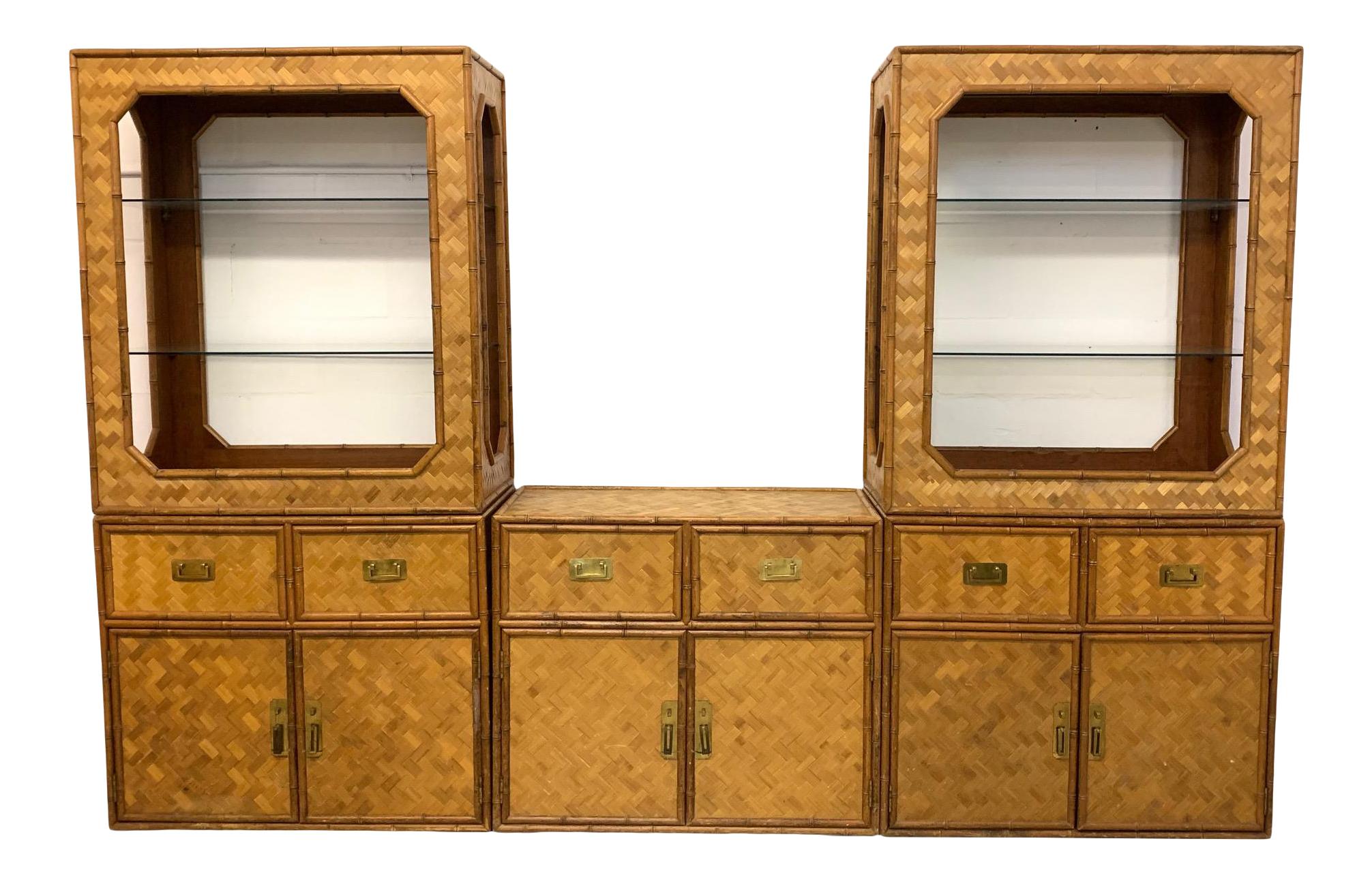 Large 3-piece wall unit consists of matching bookcase towers and a center cabinet. Faux bamboo rattan detailing and full basketweave cane veneer. Brass Campaign style hardware. Good vintage condition with minor imperfections consistent with age.
 