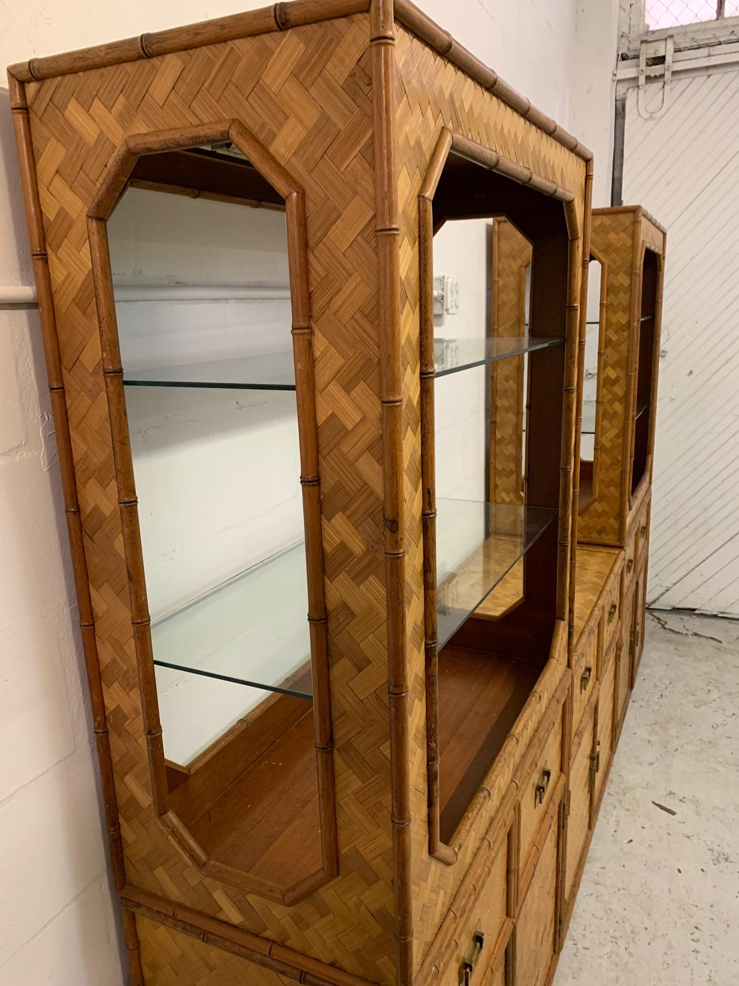 Large 3-piece wall unit consists of matching bookcase towers and a center cabinet. Faux bamboo rattan detailing and full basketweave cane veneer. Brass campaign style hardware. Good vintage condition with minor imperfections consistent with age.
 