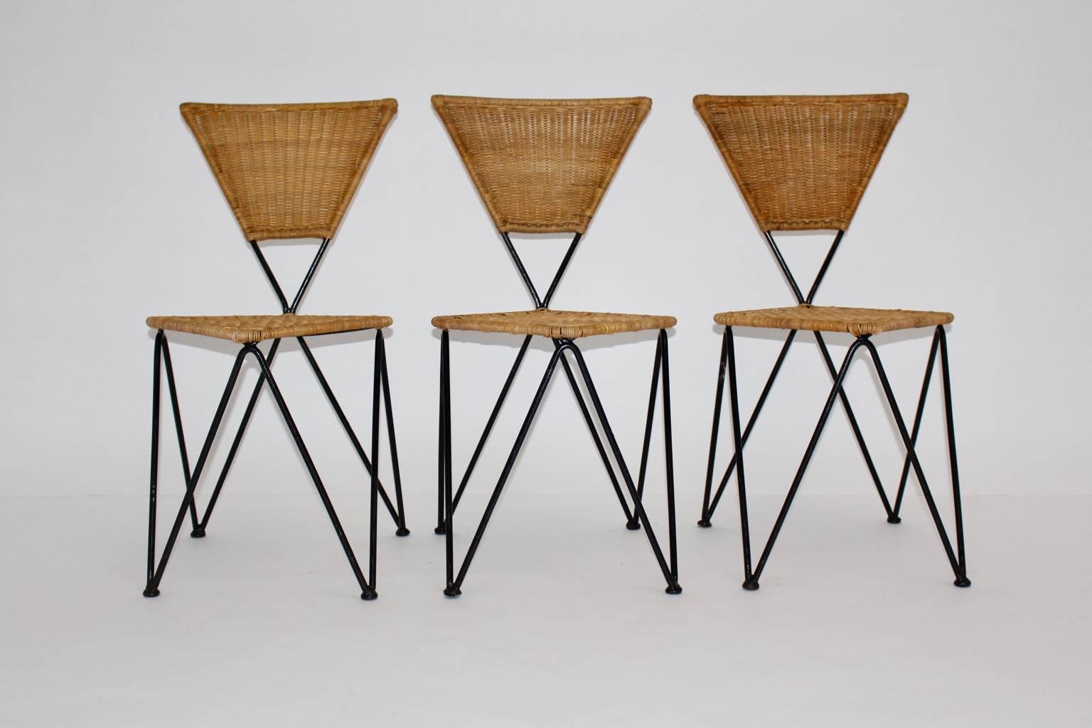 Mid Century Modern wicker vintage set of three dining chairs or patio chairs for indoor and outdoor by Karl Fostel Sen´s Erben for Sonett, Vienna.
The legs from black lacquered metal show a hairpin like shape while the seat and the back were made of