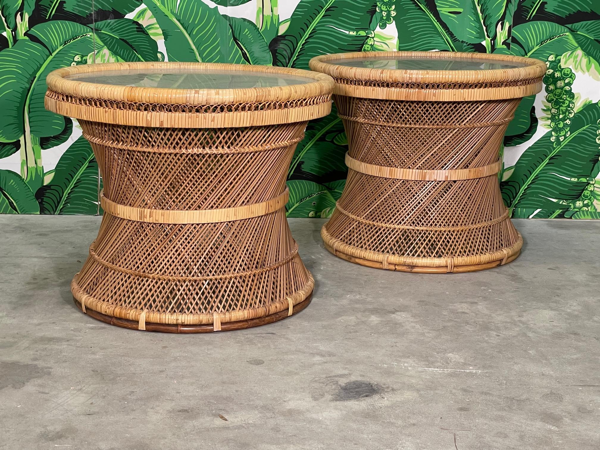 Pair of vintage wicker side tables feature an hourglass shape and glass tops. Design resembles that of the iconic Peacock, or 
