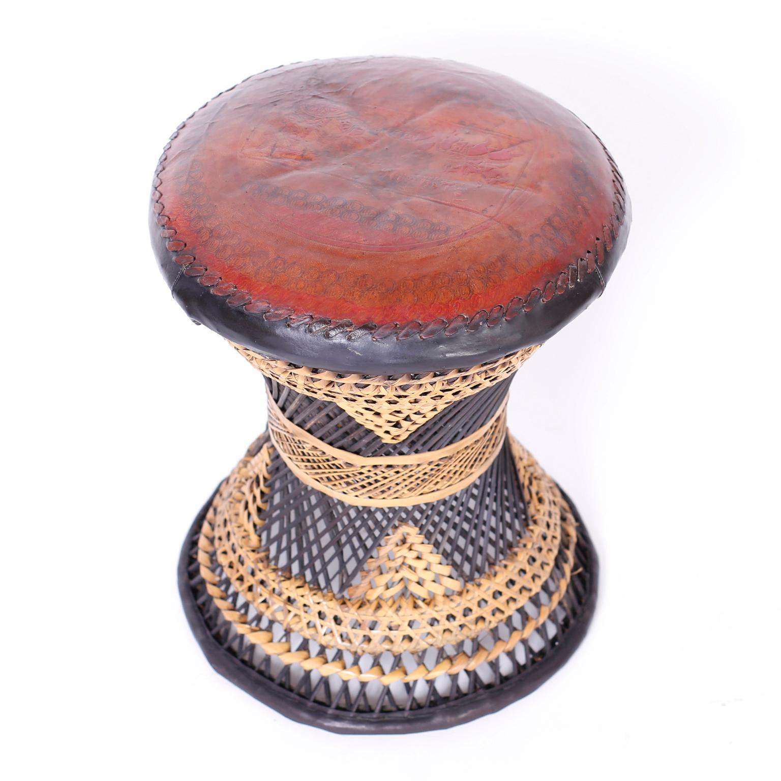 Footstool with a lush leather top embossed with a classical scene over a woven wicker base having an hourglass form.