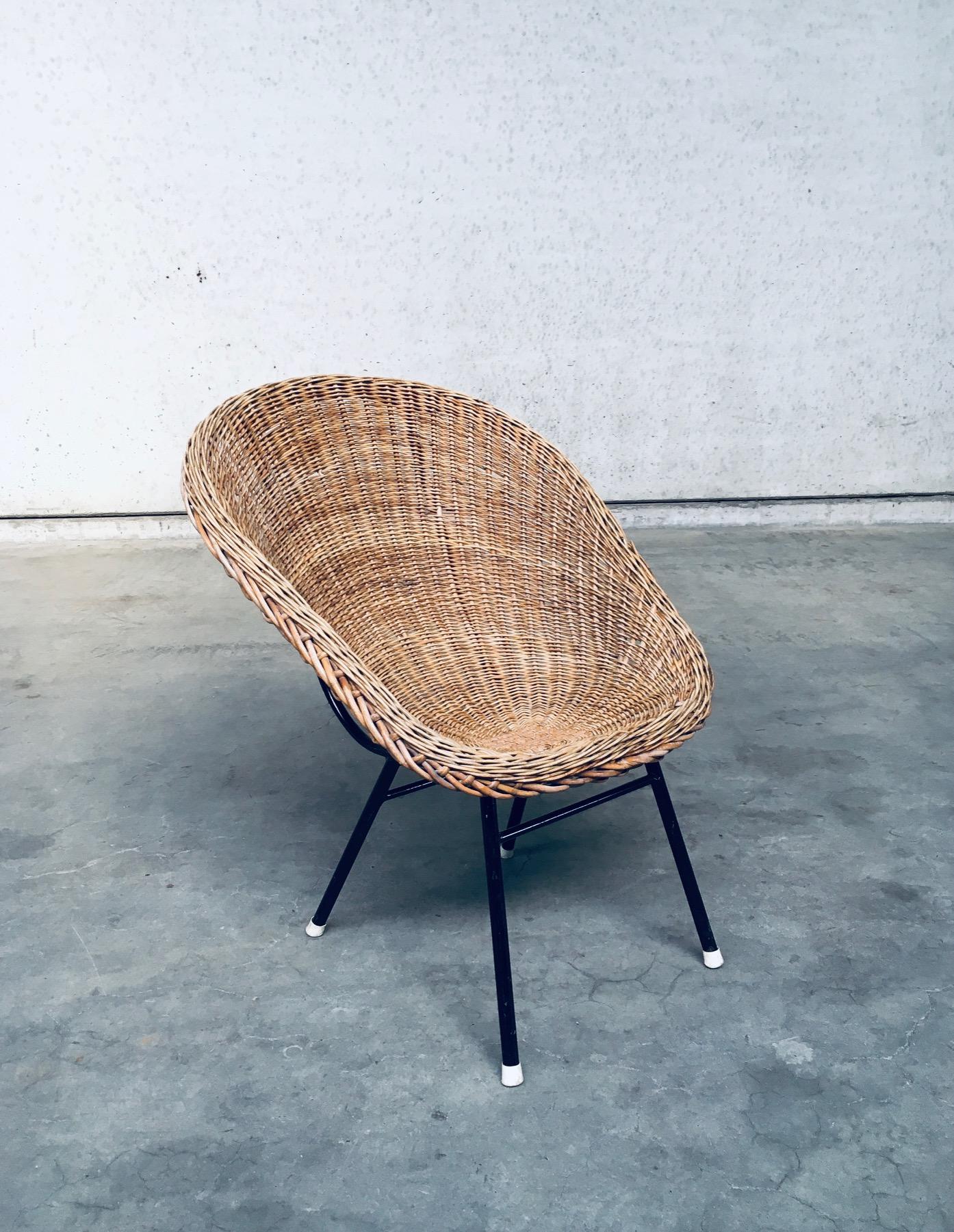 Vintage Midcentury Modern Dutch Design Wicker Lounge Chair in the Style of Dirk Van Sliedregt for Rohé Noordwolde. Made in the Netherlands, 1960's. Wicker rattan seat on black lacquered steel frame with original white plastic covers on the feet.