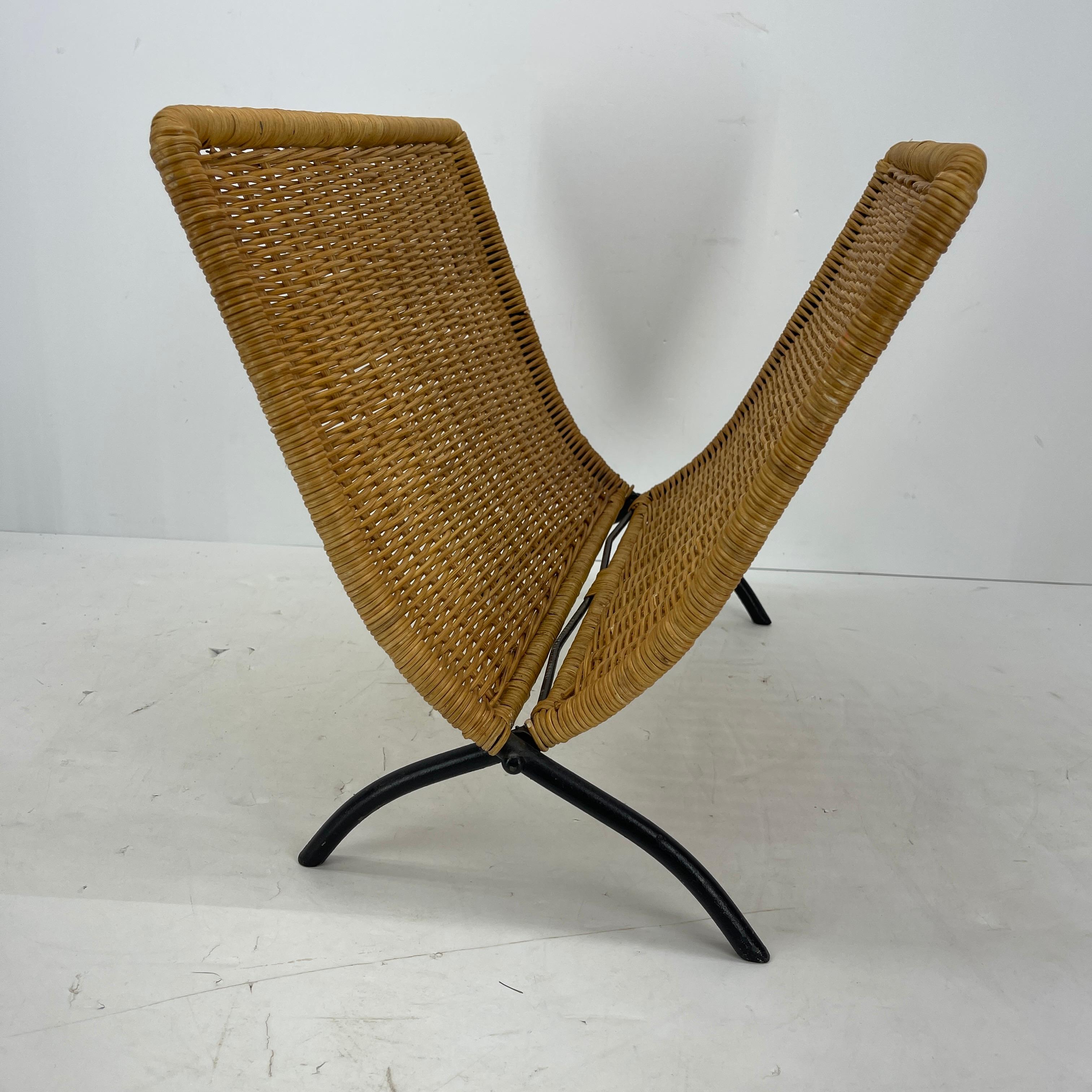 Mid-Century Modern wicker folding magazine rack with black metal feet in the style of Jacques Adnet.
This nifty magazine rack has solid wicker frame and sides and is enhanced with it's black metal feet. Standing strong and ready to hold up to a