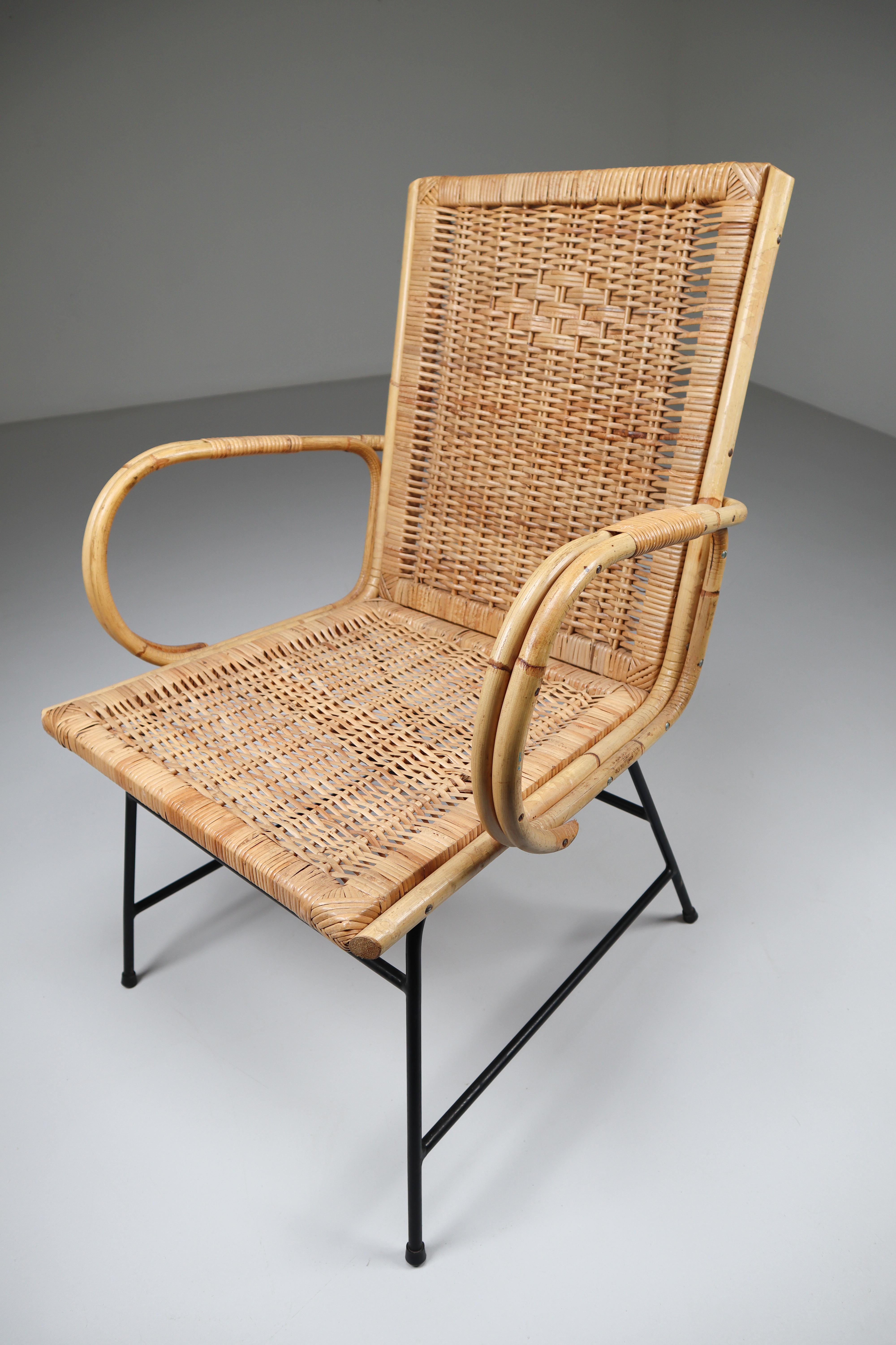 Wicker midcentury armchair designed and produced in France during the 1960s. The chair is made from handwoven wicker for the seat and he frame is made of black lacquered steel. They are comfortable to sit in and create an inviting sitting