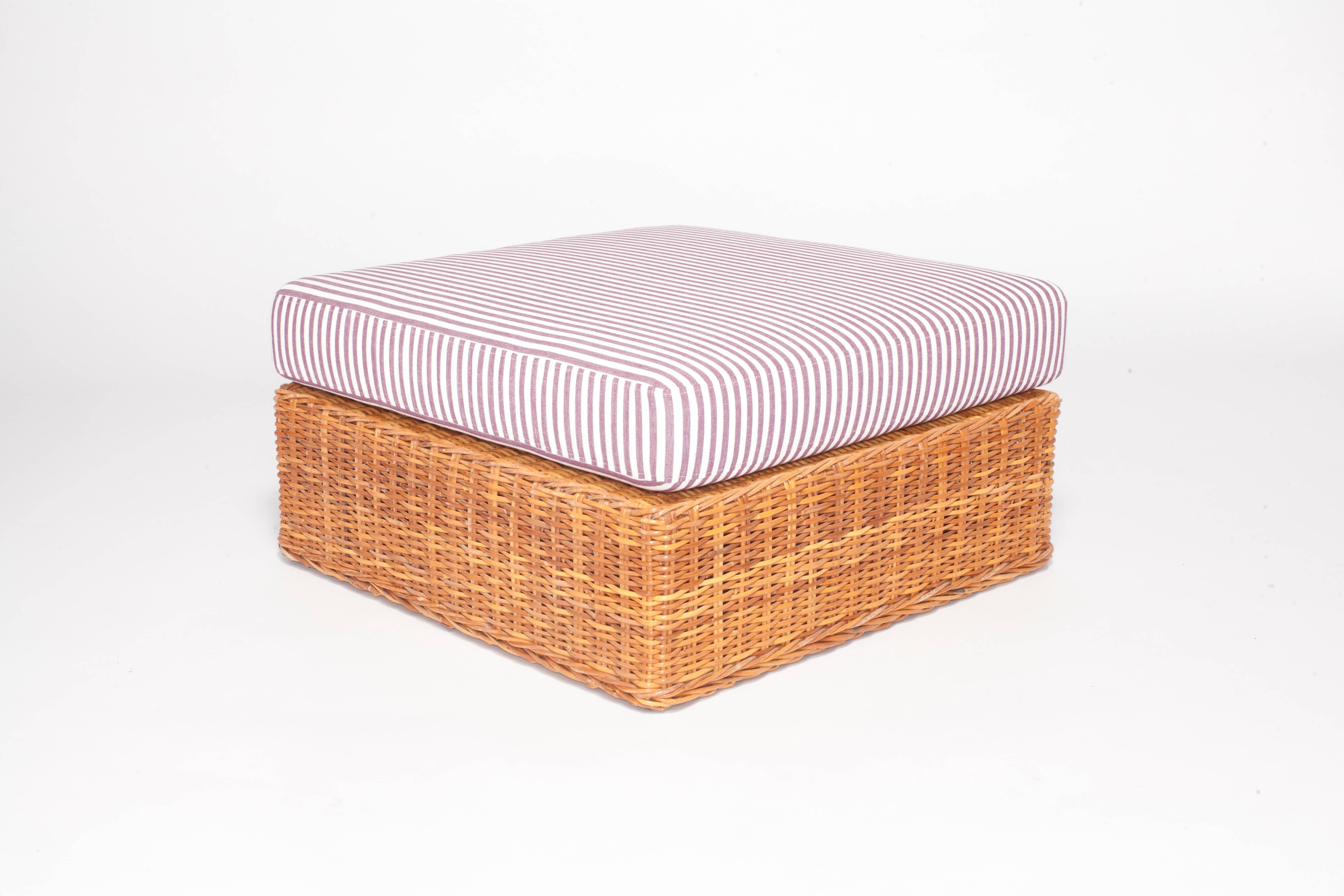 Wicker ottoman newly upholstered in purple striped fabric.