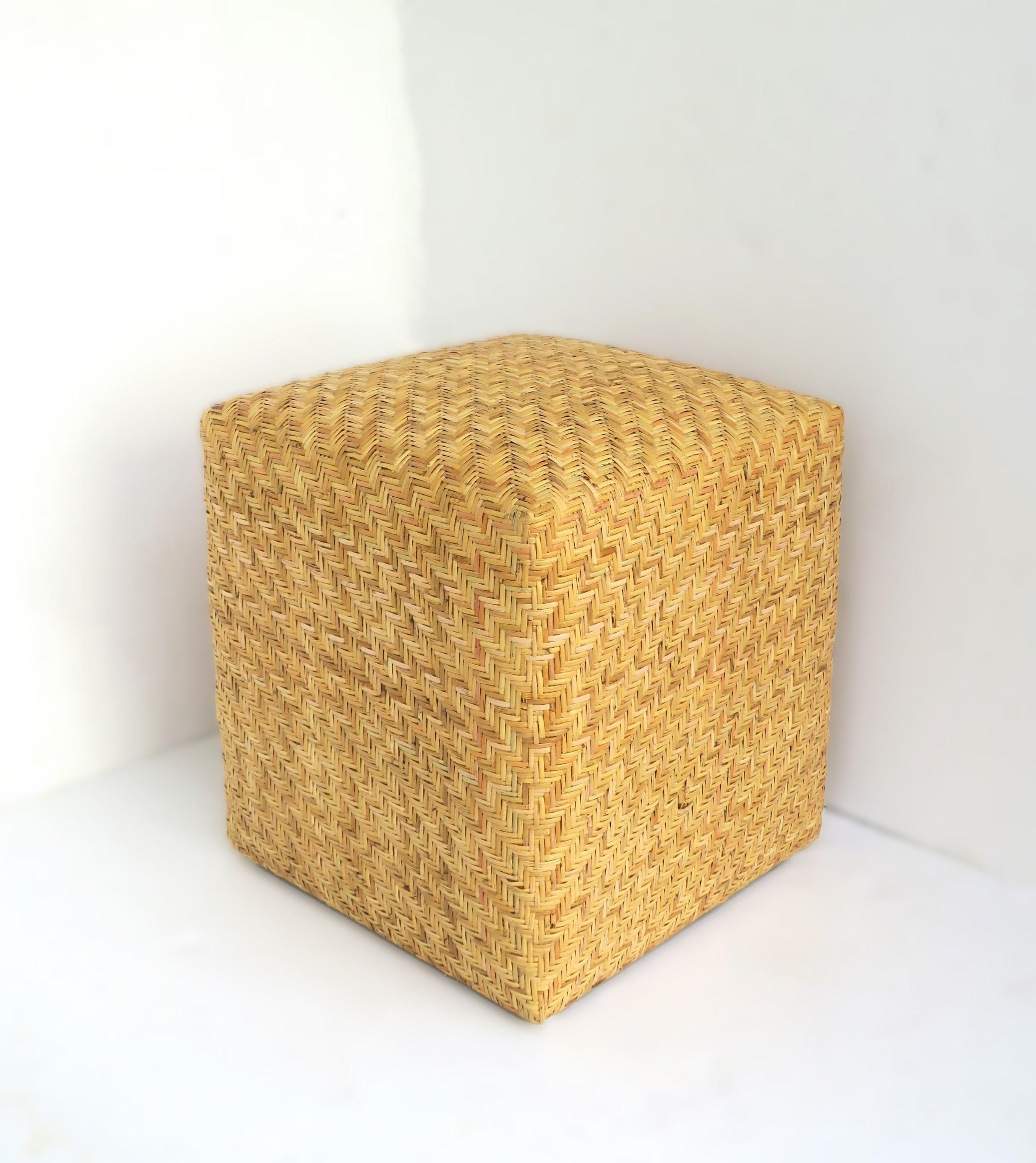 A blonde/tan weaved wicker pedestal stool ottoman seat. An all-wicker weaved stool with a chevron-esque pattern design. Seat is comfortable yet firm. Piece could also double as a footstool or side/drinks table with firm environment on top, e.g.