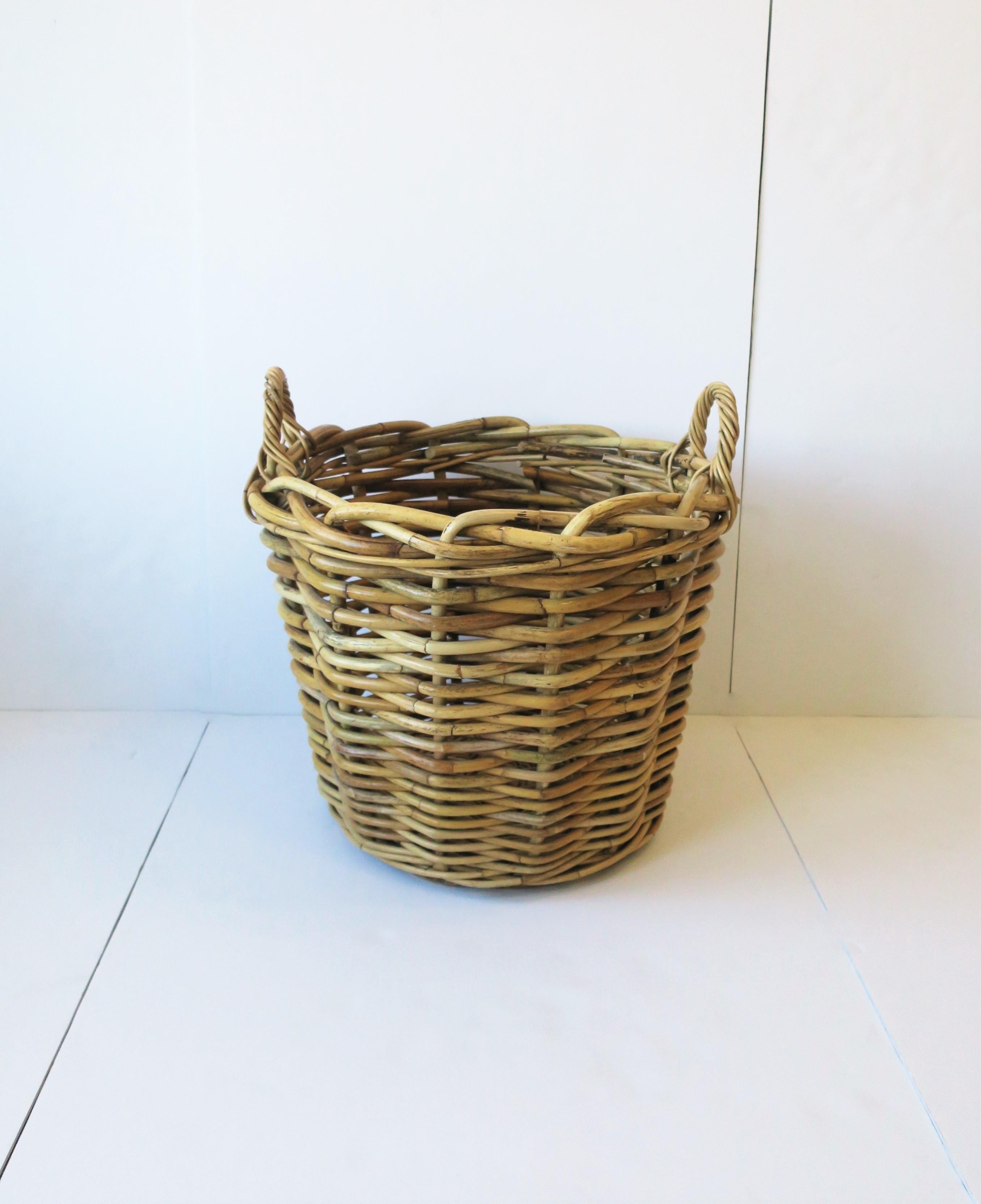 A substantial wicker rattan basket with loop handles, circa mid to late-20th century. Basket is strong and well made. Piece could work as a standalone decorative piece, to hold fresh rolled towels, for laundry, cachepot for plant pot, etc.