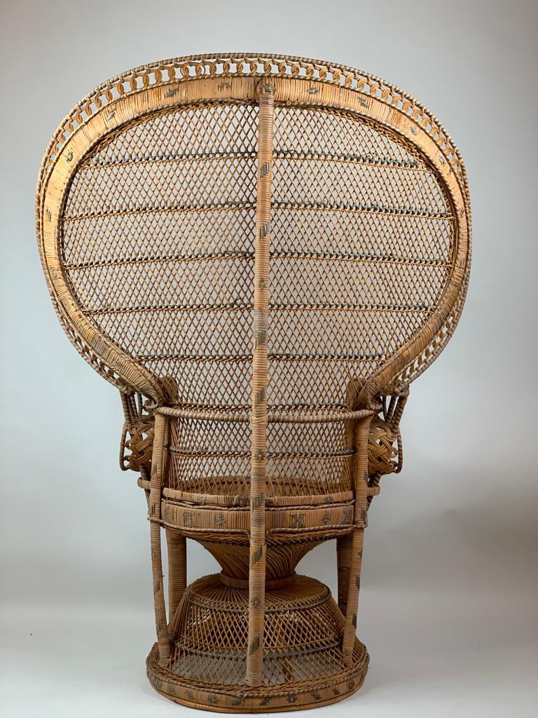 Wicker rattan chair made famous by the film Emmanuelle, ca. 1970's. The chair has expertly woven wicker and cane with a large-scale fan back, portraying a peacock’s tail.
The Peacock chair became the Emmanuelle Chair In the 1970s. This throne-like