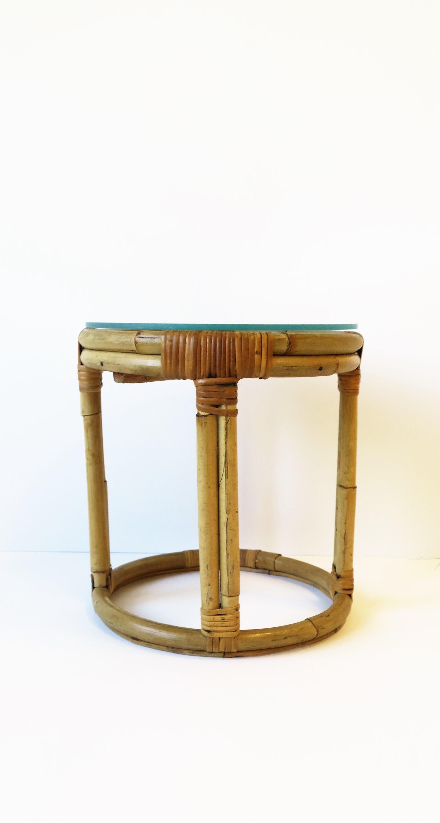 A small round wicker rattan side or drinks table with glass top, circa mid-20th century. Easy to move around and a convenient size. Other uses may include a plant stand, etc. Dimensions: 12