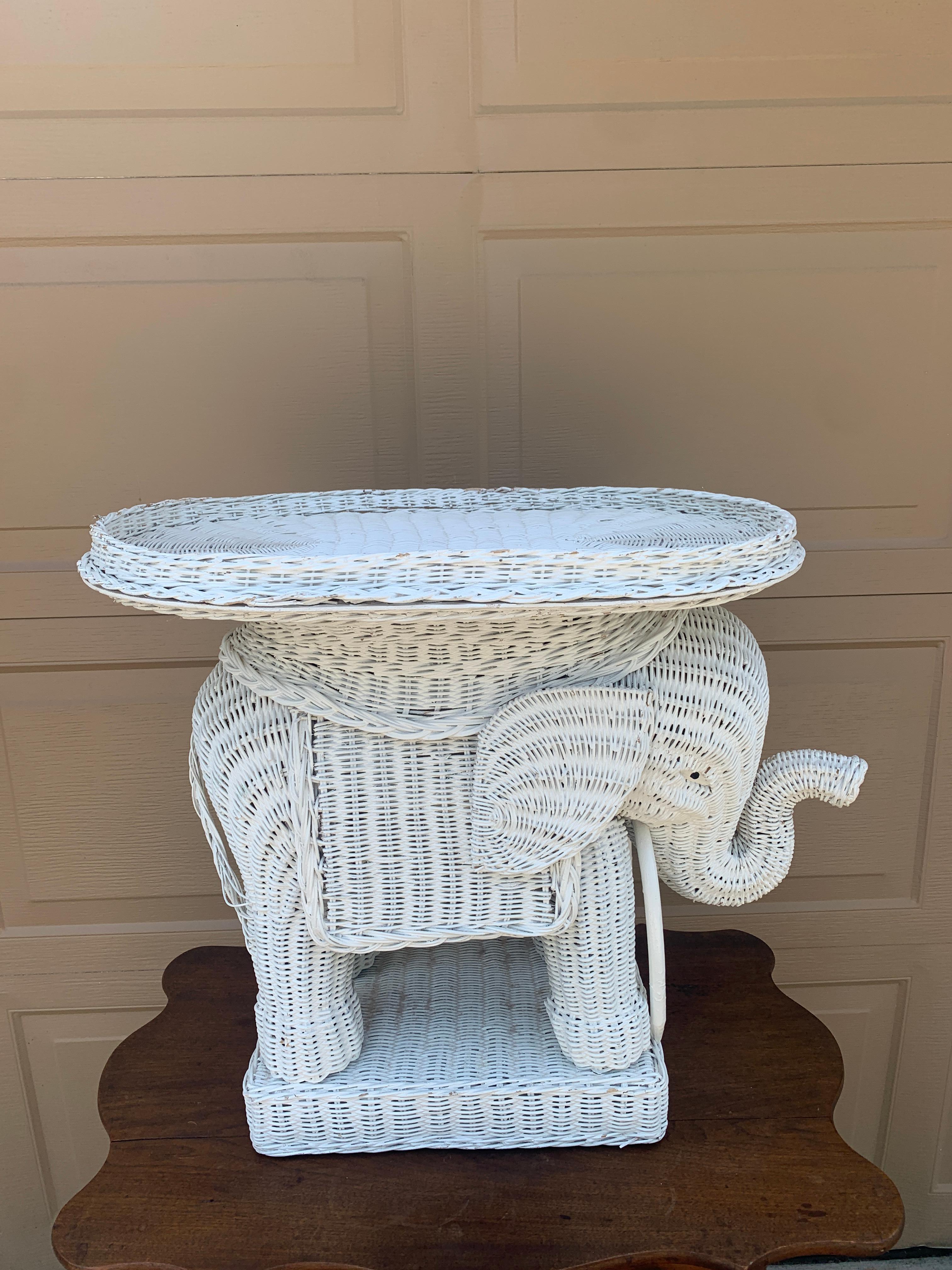 Un charmant tabouret de jardin ou table d'appoint en rotin en forme d'éléphant blanc en osier du milieu du siècle, avec plateau amovible.

USA, Circa 1970s

Mesures : 28 