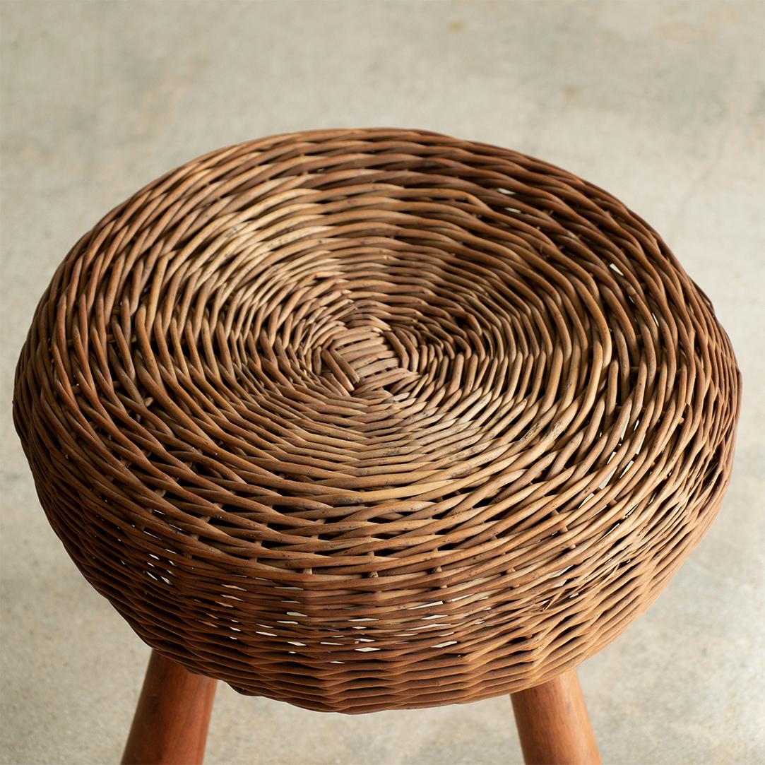 1950's circular wicker stool with three wood legs by Tony Paul. All original with nice age and patina.