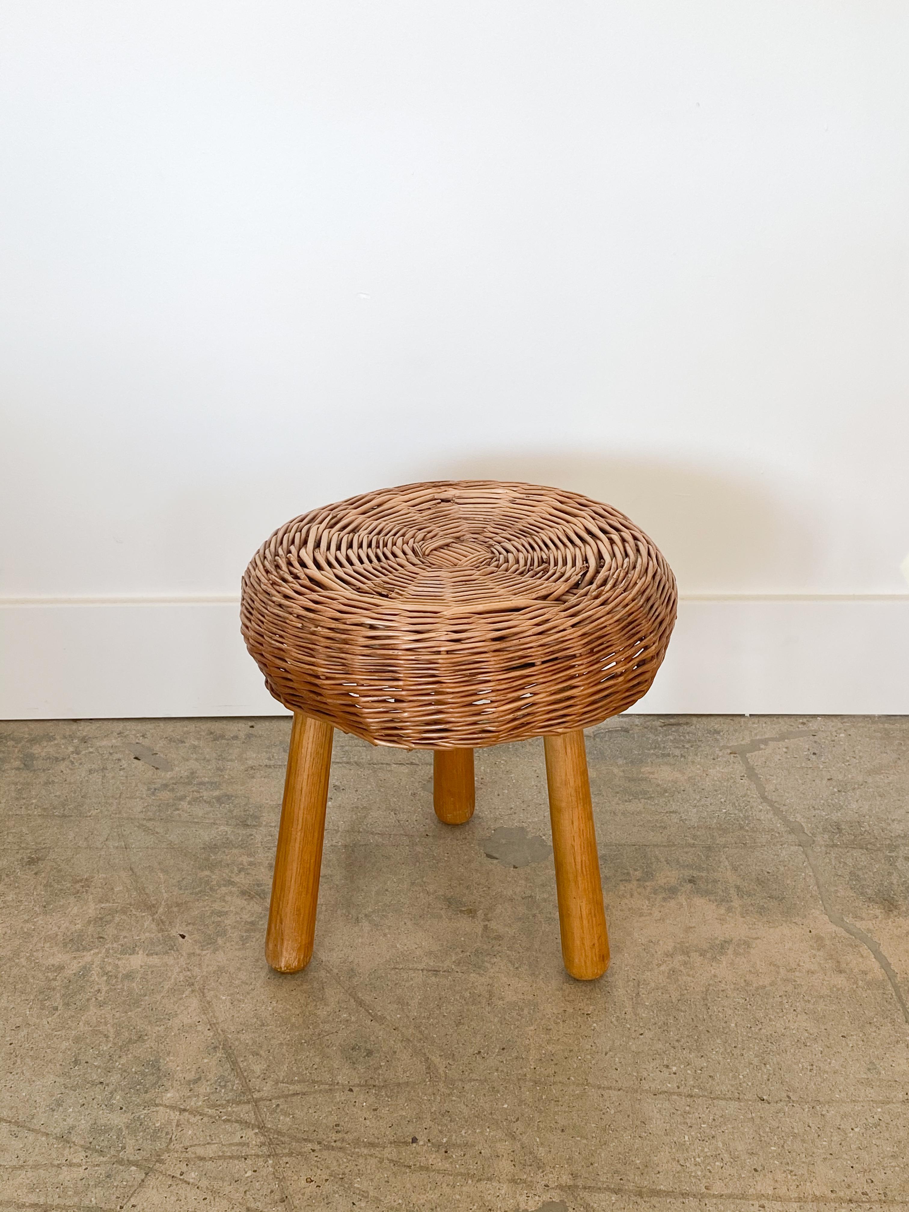 Circular wicker stool with three wood legs in the style of Tony Paul from the 1950s. All original with small pieces of wicker missing. See photos.