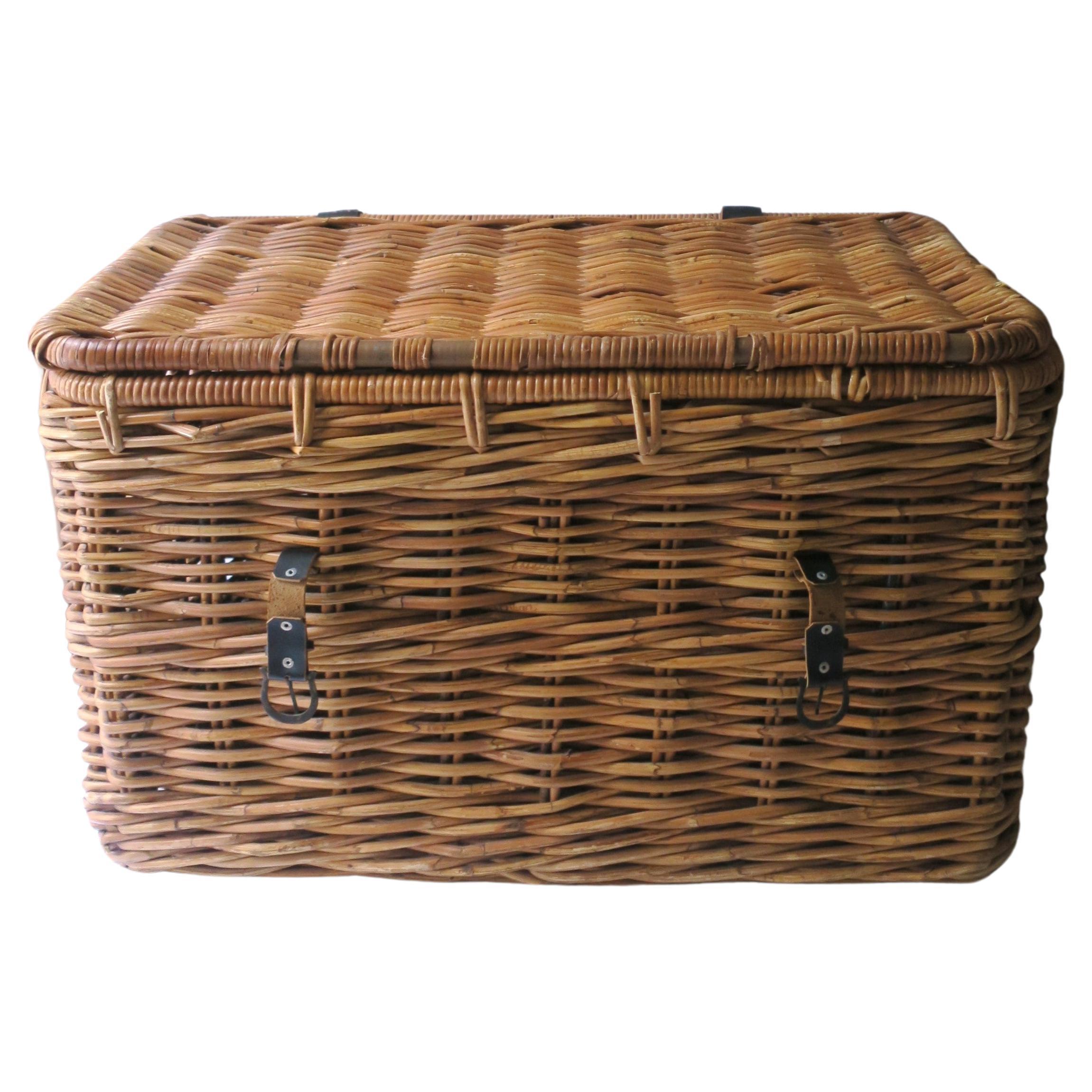 A wicker trunk basket with lid and handles, in the rustic or country style, circa early to mid-20th century. Piece has handles on either side and an easy open/close lid. Use trunk basket for laundry, playroom toys, other storage, firewood log
