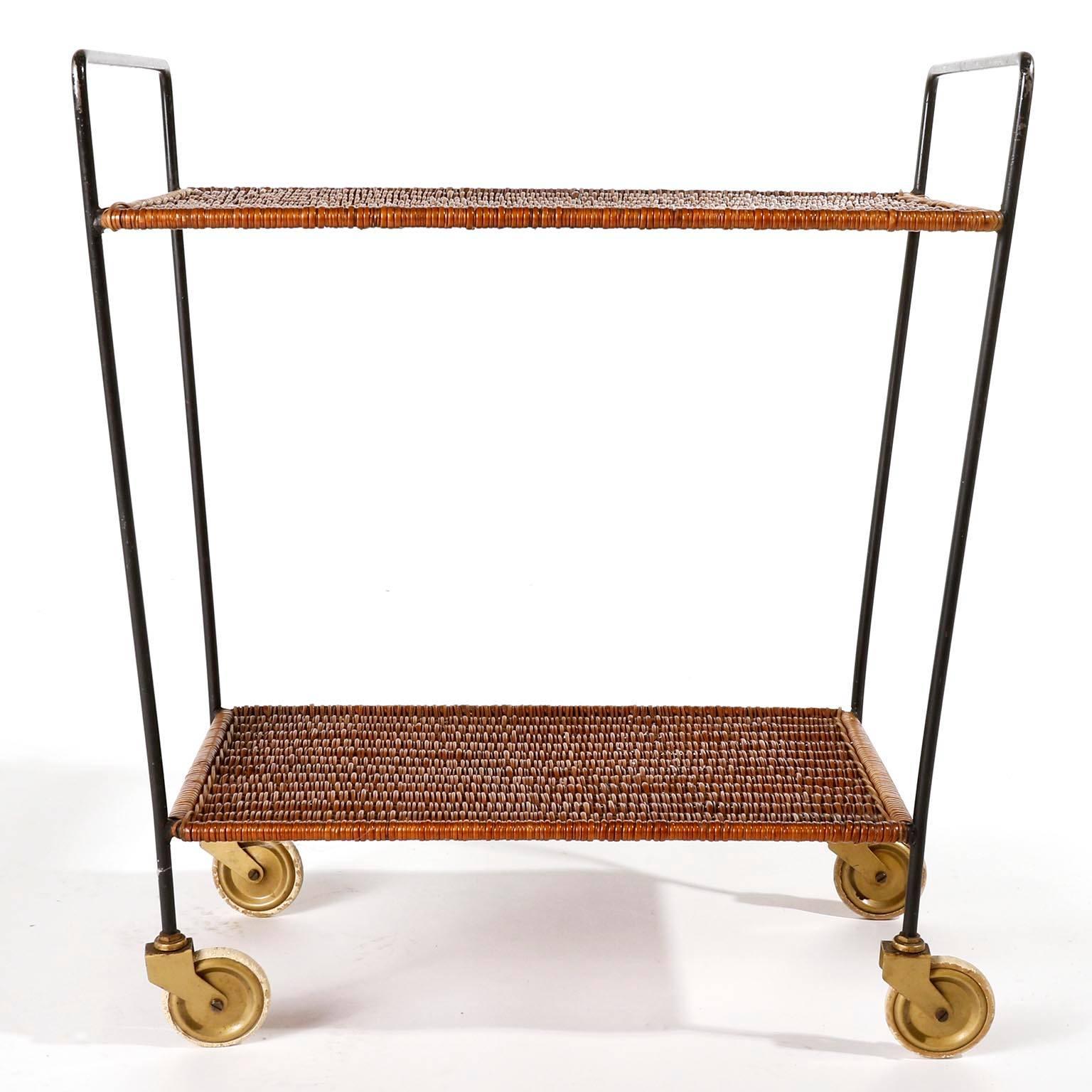 A beautiful trolley table or tea cart made of a black painted metal frame with wicker shelves manufactured in midcentury in Austria, circa 1950.
The wicker is in excellent condition. Wear of use on the metal particularly on the handles.
The trolley