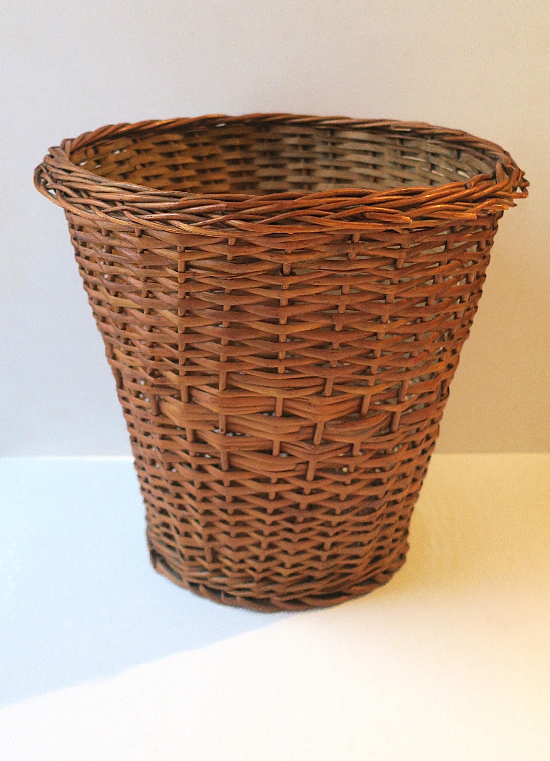 A vintage European wicker wastebasket trash can with braided edge, circa mid to late-20th century, 1960s. 1970s, Yugoslavia. Piece is a medium brown hue, a great item for a bathroom, powder room, office, library, etc., many places. Very good