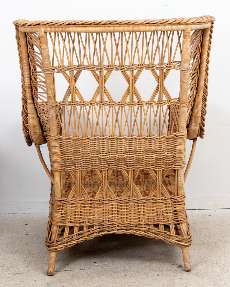 Circa 1990s wicker wing back armchair with braided ribbon detail throughout. The seat back also features woven x-shaped trim. Made in the United States. Please note of wear consistent with age.