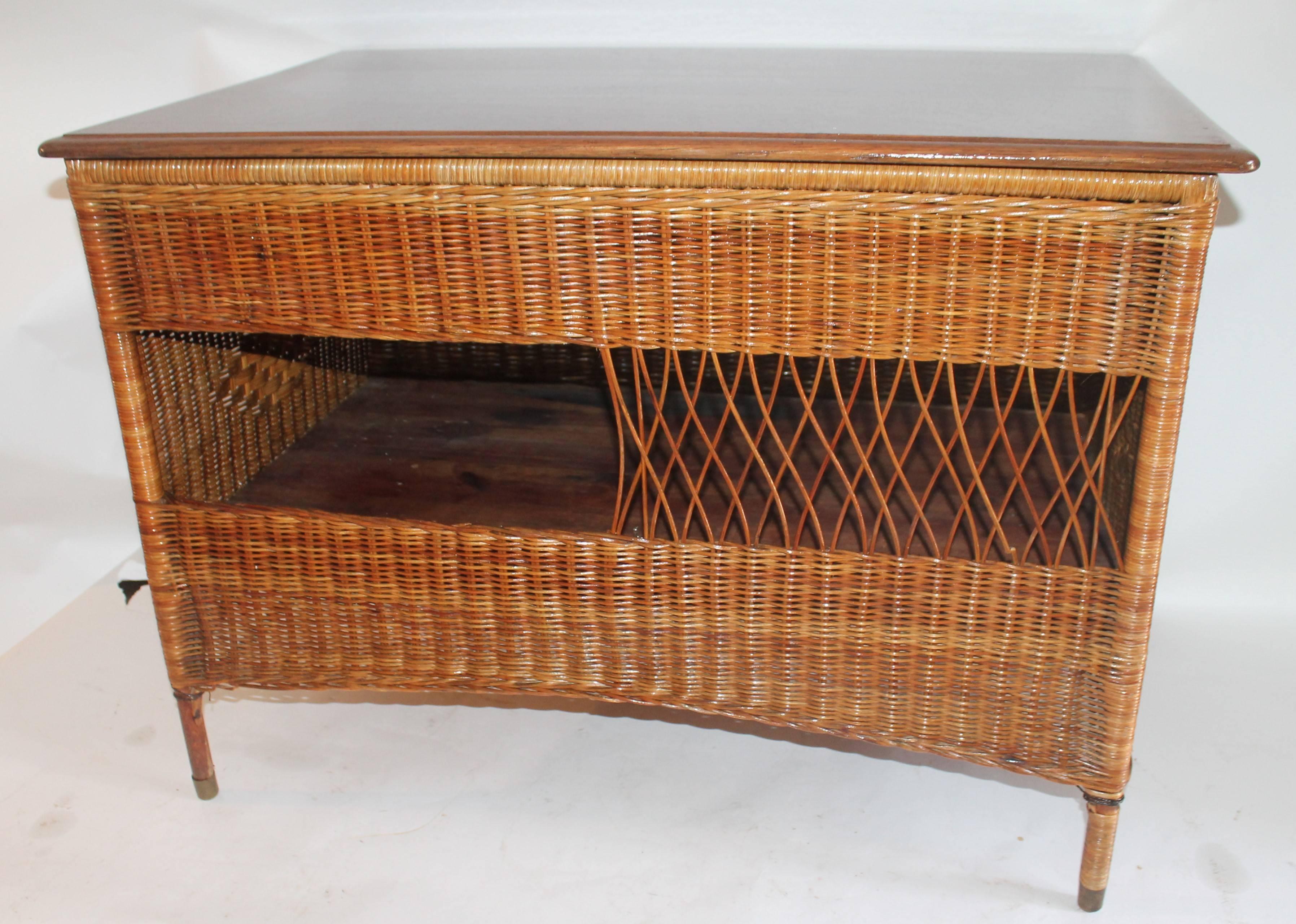 This most unusual wicker work table with a oak lift top in fine condition. Not sure if it was a work or counter table in a sewing store. Bar Harbor style but unsigned. With a natural stain and varnish surface.