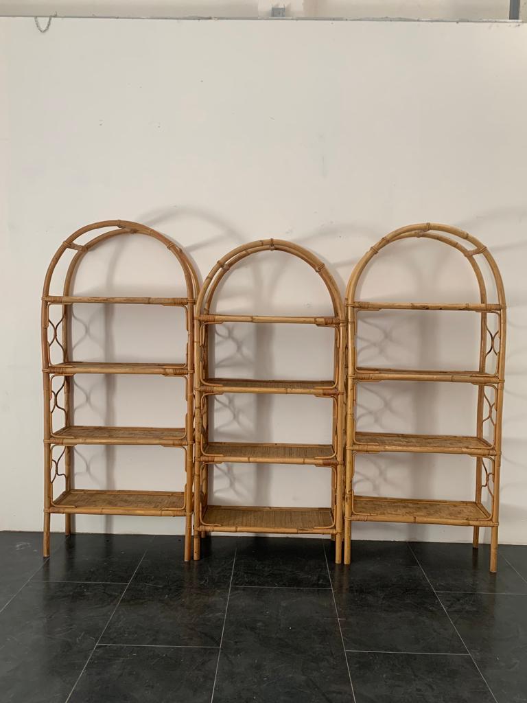 Composition of three arched bamboo and wicker bookcases, 1960s. The two side ones are identical, the middle one belongs to the same collection and period but is lower and has more intensely woven wicker shelves. The two large ones are 183 cm high,