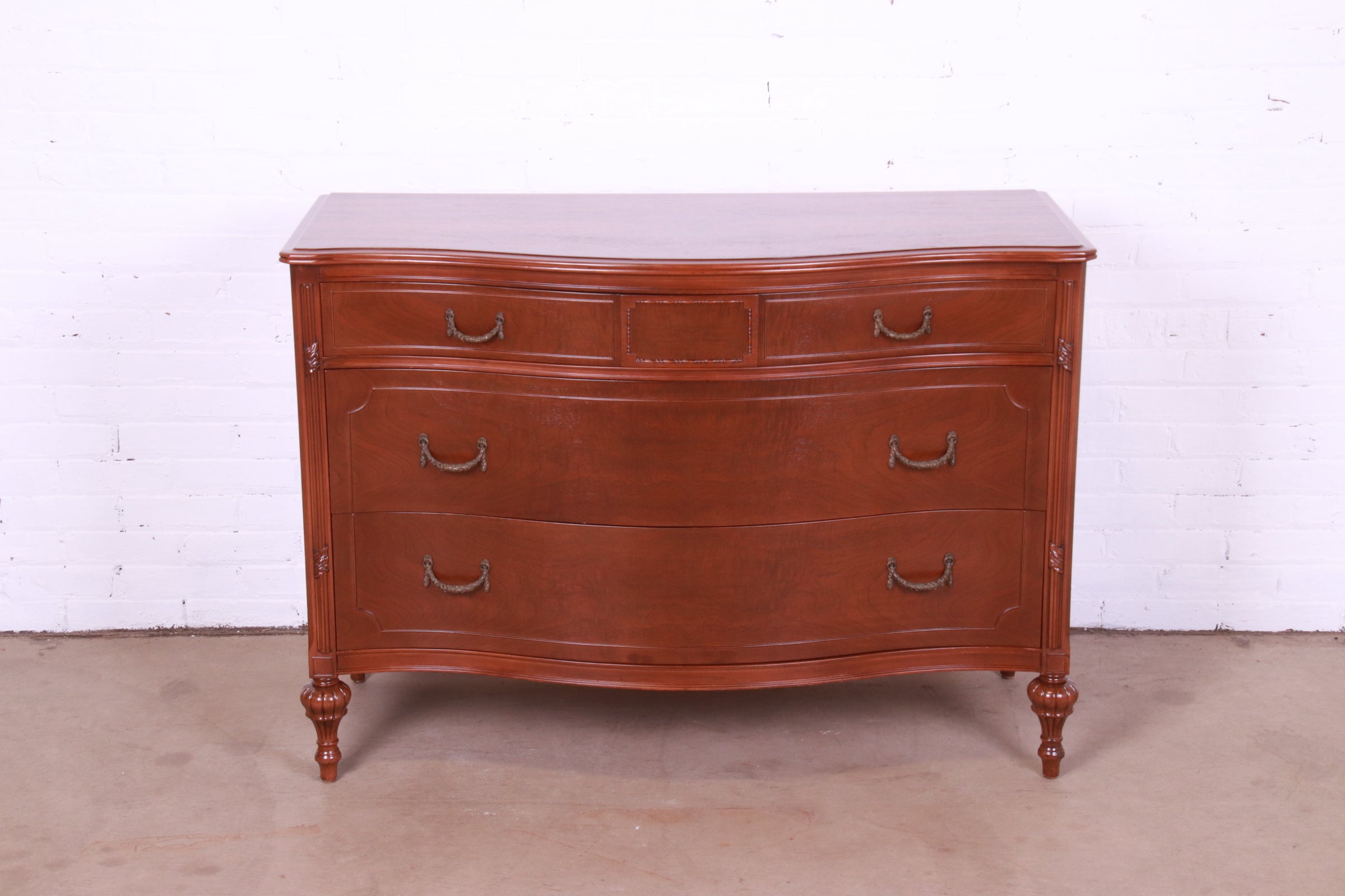 An exceptional French Regency Louis XVI style bow front three-drawer dresser

By Widdicomb

USA, Circa 1920s

Carved burled walnut, with original brass hardware.

Measures: 48