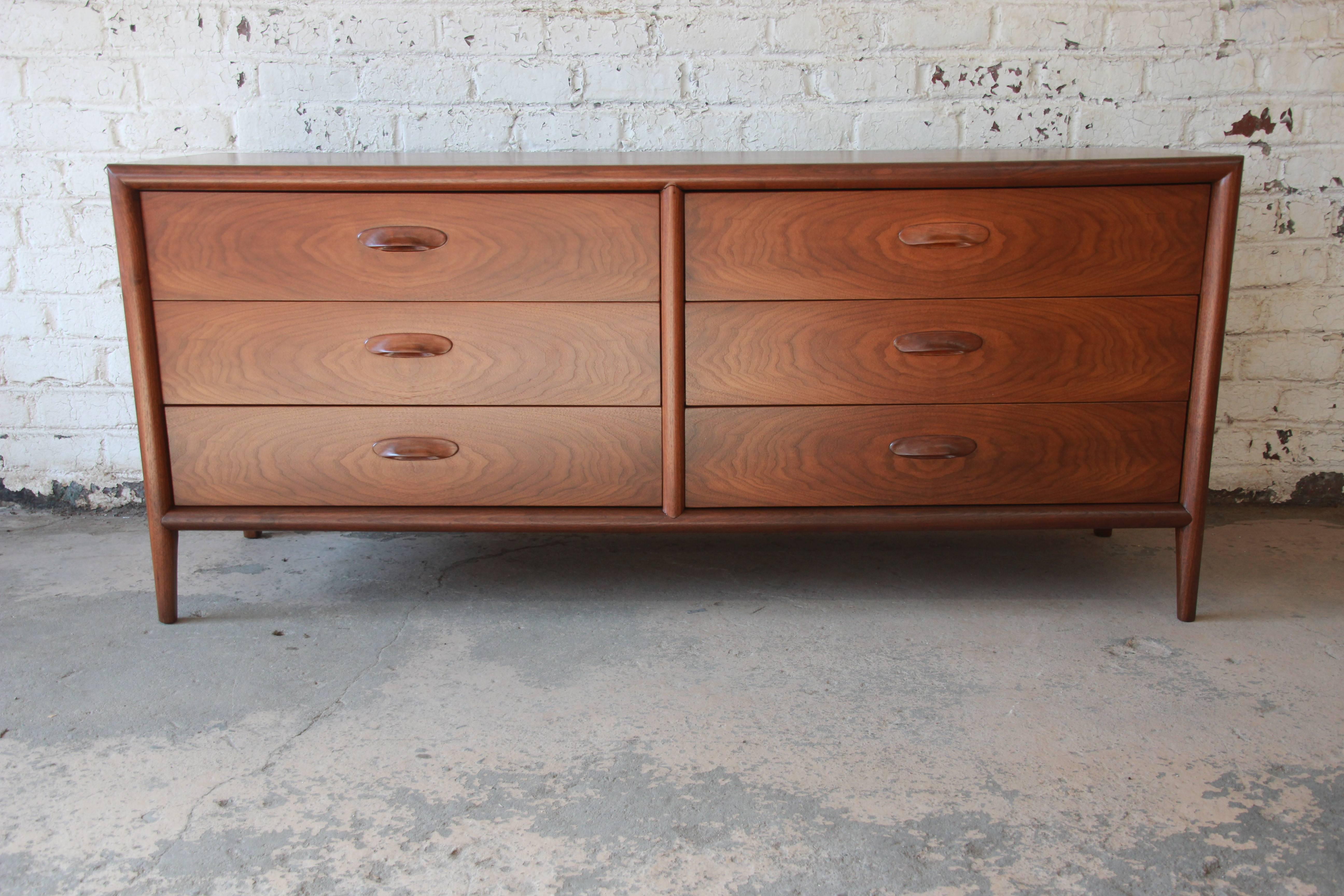 A rare and exceptional Mid-Century Modern walnut six-drawer dresser or credenza by Widdicomb Furniture Co. of Grand Rapids. The dresser features gorgeous walnut wood grain and sculpted wood drawer pulls. It offers ample room for storage, with six
