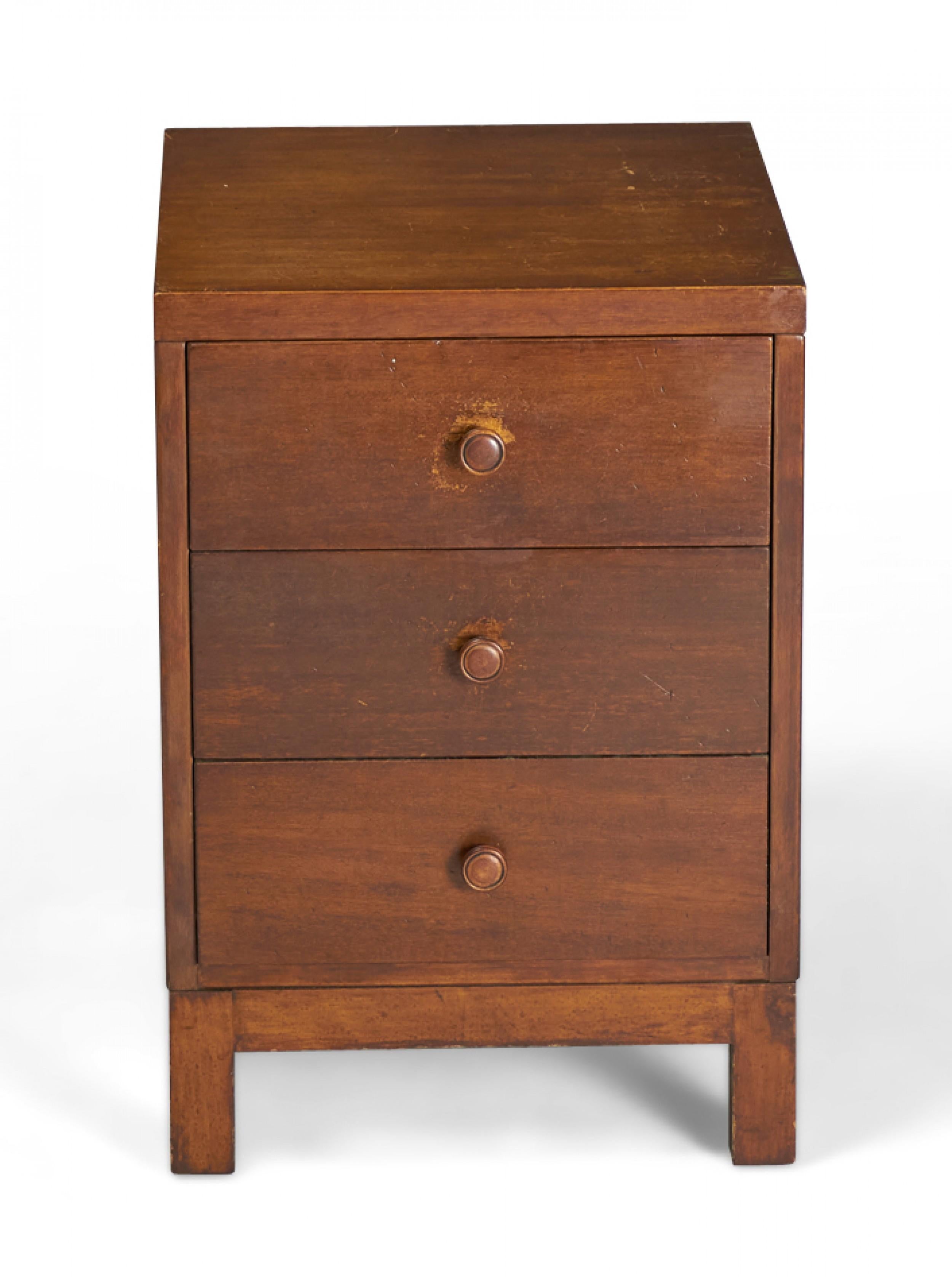 American mid-century dark stained walnut bedside table / nightstand with three drawers with circular wooden drawer pulls resting on four square legs. (WIDDICOMB MODERN)(Similar nightstands: DUF0155A, DUF0155B)
 