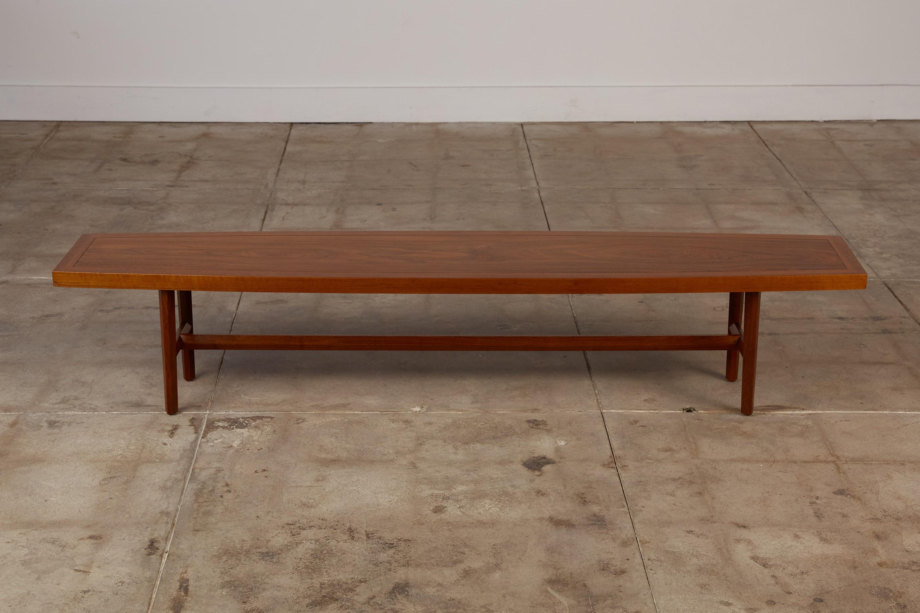 Walnut coffee table by Grand Rapids, Michigan-based Widdicomb, c.1950s. The table features a flared rectangular top on faceted tapered legs and faceted stretchers on the length and width. This design is similar to tables that George Nakashima did