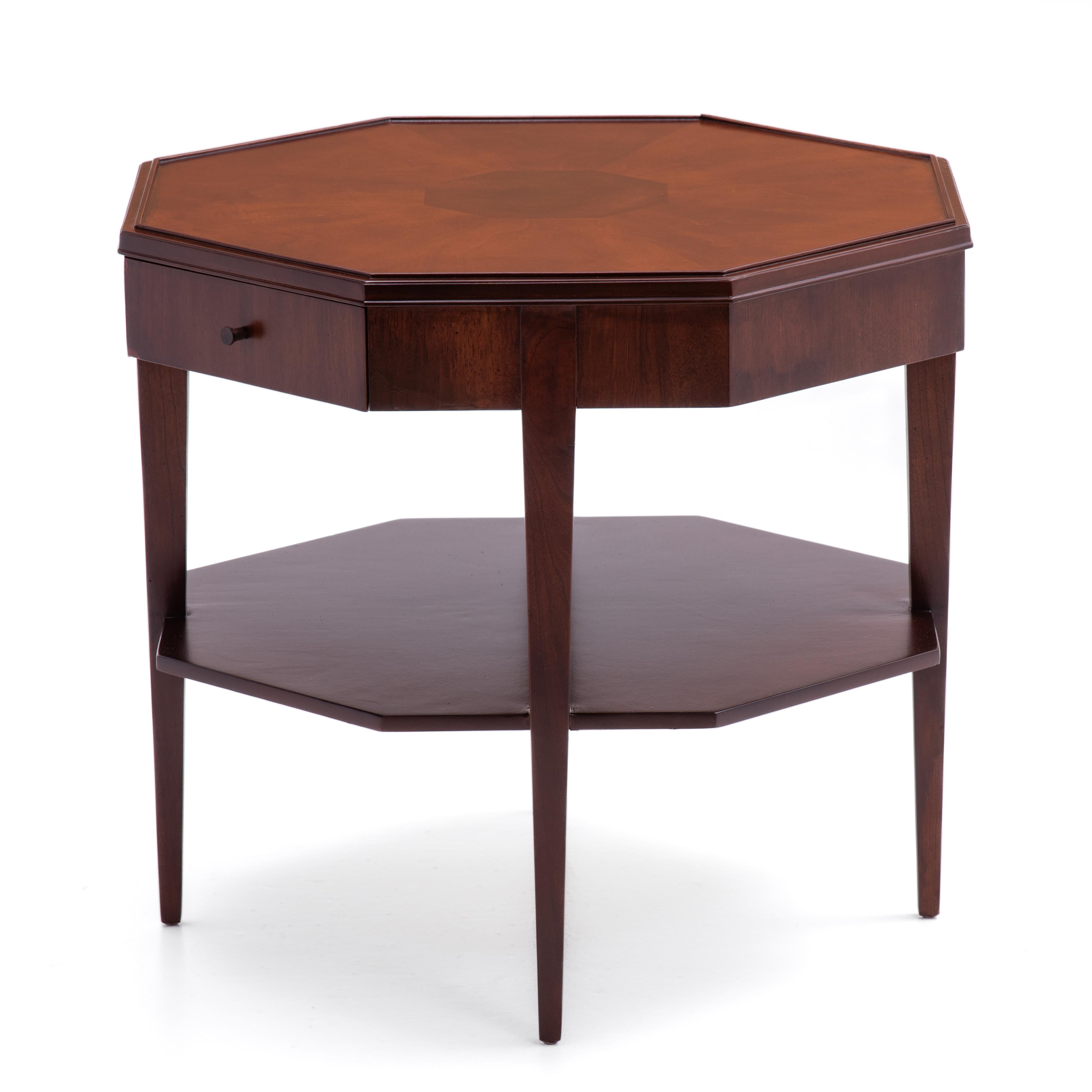 A versatile Widdicomb lamp, side or end table with tapered legs and an octagon shaped, book matched top and a single drawer. The point to point or diagonal distance of the top is 26” .