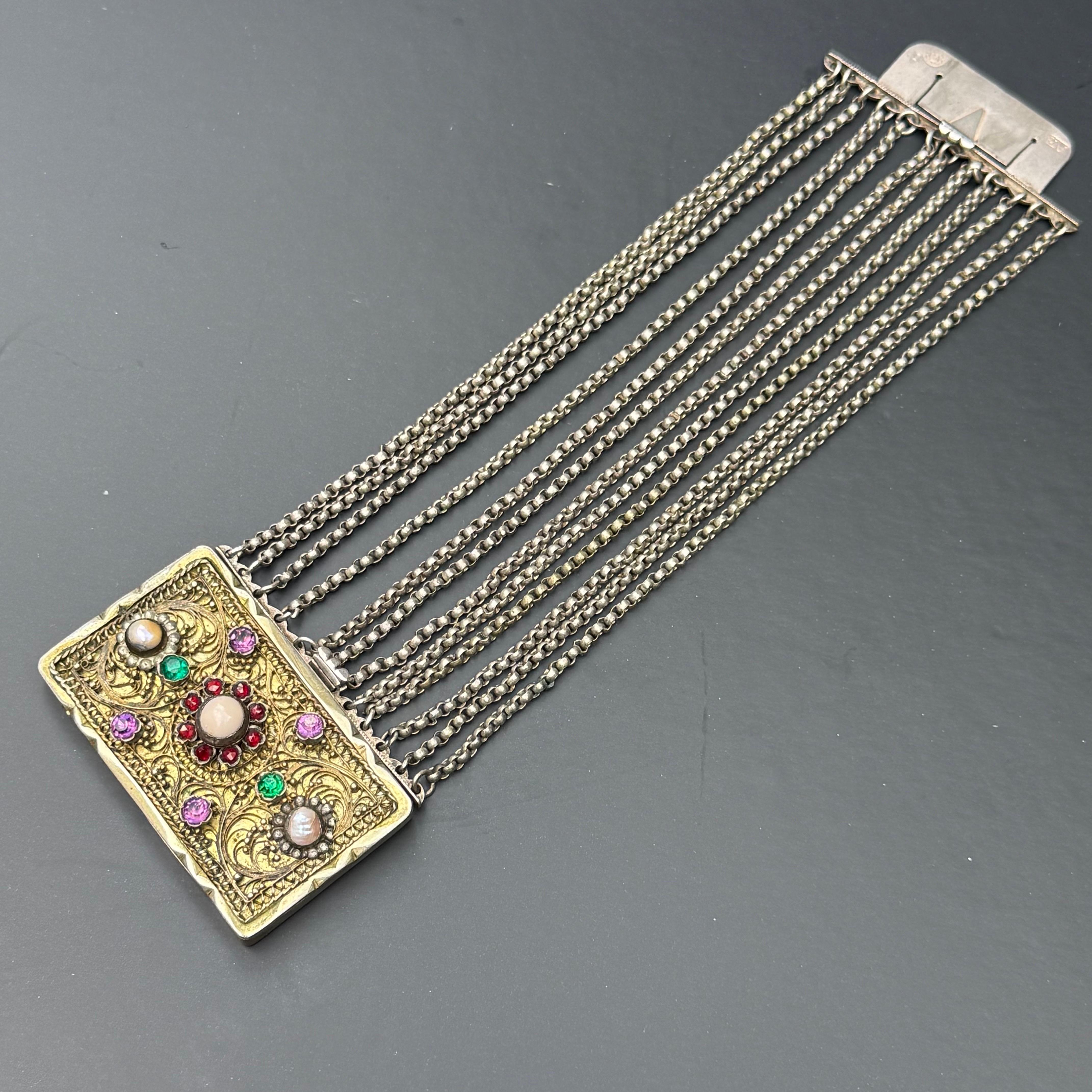 Magnífico ejemplo de la artesanía austriaca de la época victoriana, este brazalete antiguo de doble tono es a la vez visualmente cautivador y técnicamente sofisticado. Destaca su gran cierre central extraíble, ricamente adornado con filigrana de