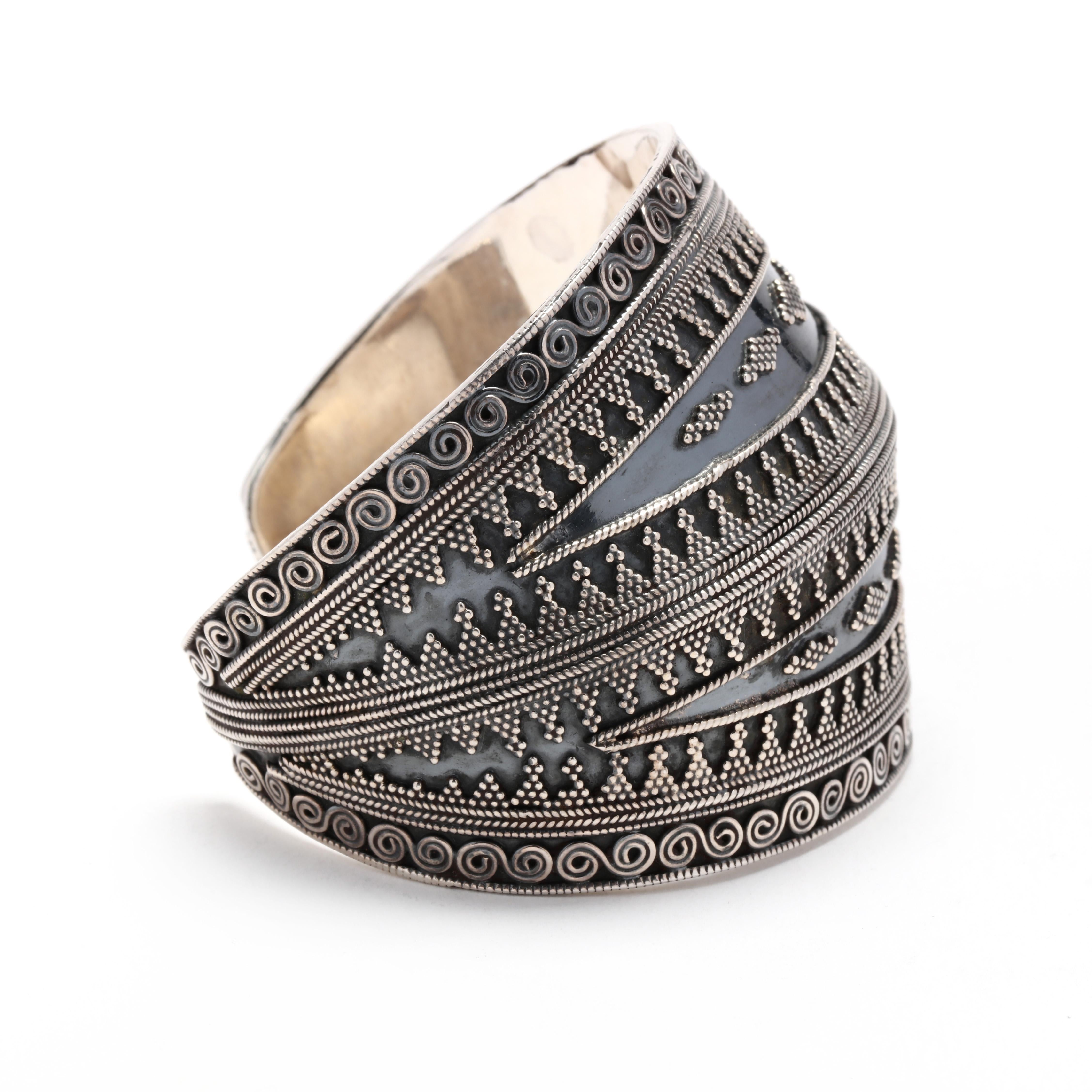 A sterling silver wide beaded tribal cuff bracelet.  This bracelet features a tribal style applied motif with beaded and coiled decoration with a raised ridge to the center.   The wide front tapers to the back and it tests as silver.

Length: 6 1/2