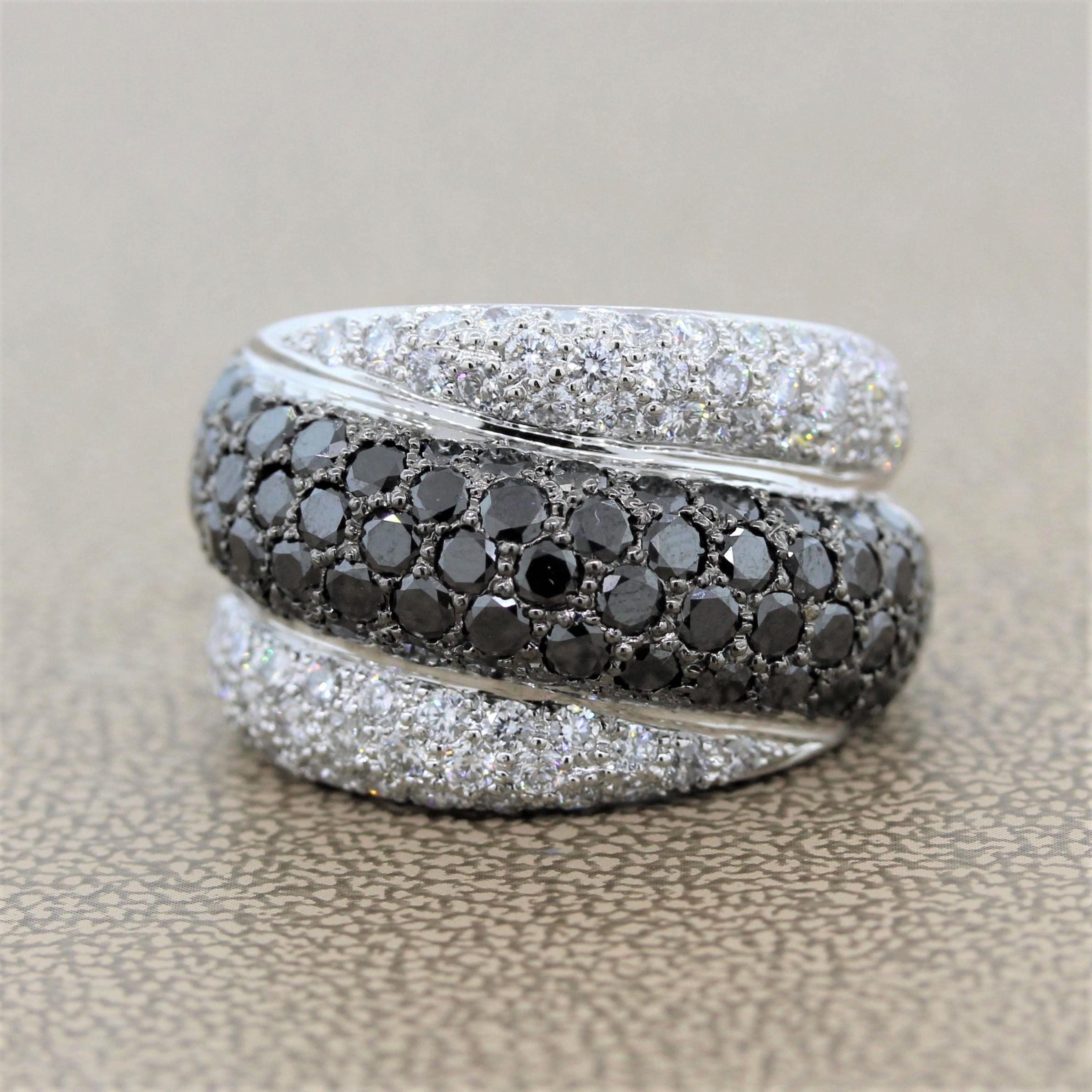A bold ring featuring 4.31 carats of black diamonds and colorless diamonds in an 18K white gold setting. A strip of round cut black diamonds prong set with black rhodium runs along the center of the band with two stripes of round cut colorless