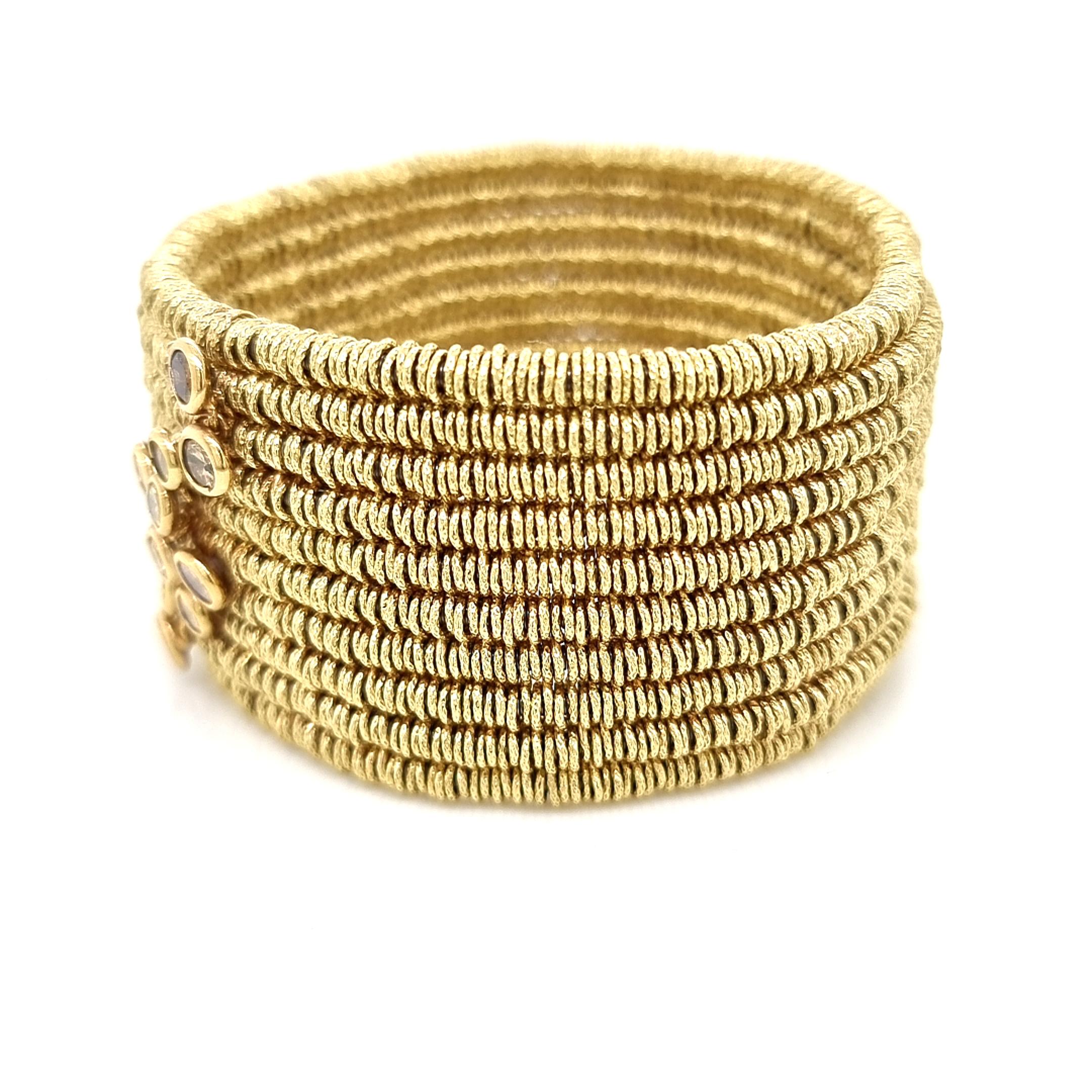 Introducing a sophisticated and contemporary statement piece, the wide bracelet features a fusion of 18K yellow gold and innovative steel spring elements, providing a seamless stretchability for a comfortable fit. An exquisite arrangement of various