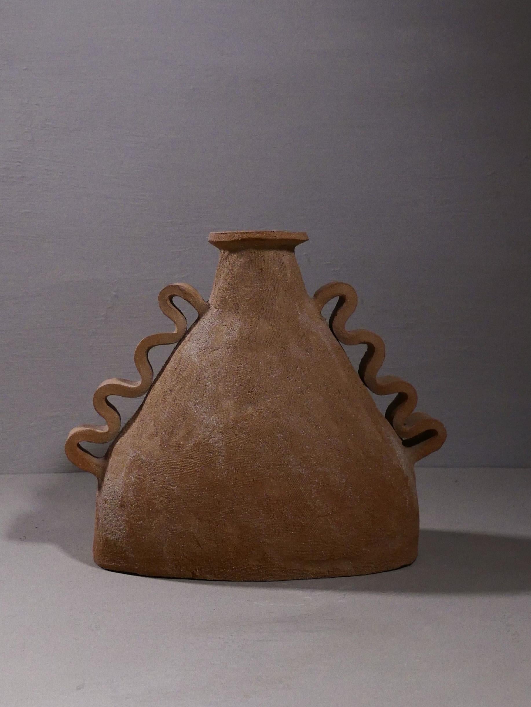 One-of-a-kind vase with wiggly handles, hand-built in Spain by artist Sophie Agullo. This piece feels like it was dug out of the ground, with a beautiful brown, sandy, textured finish. The interior is glazed with a warm white color, making the piece