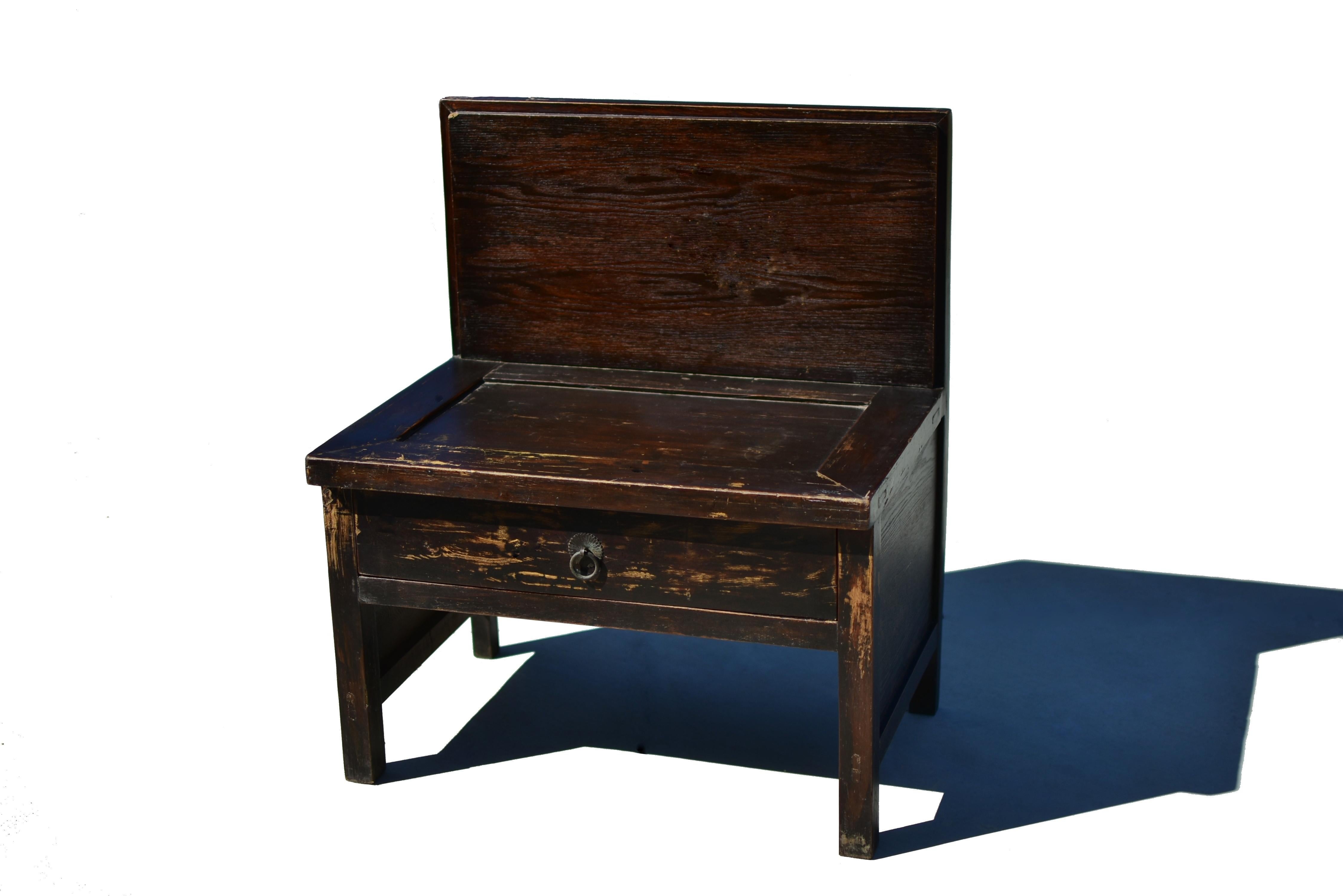 Une chaise en bois massif avec un beau dossier sculpté. La chaise est exceptionnellement large et robuste, avec un grand tiroir de rangement. Le siège est placé dans la structure du 
