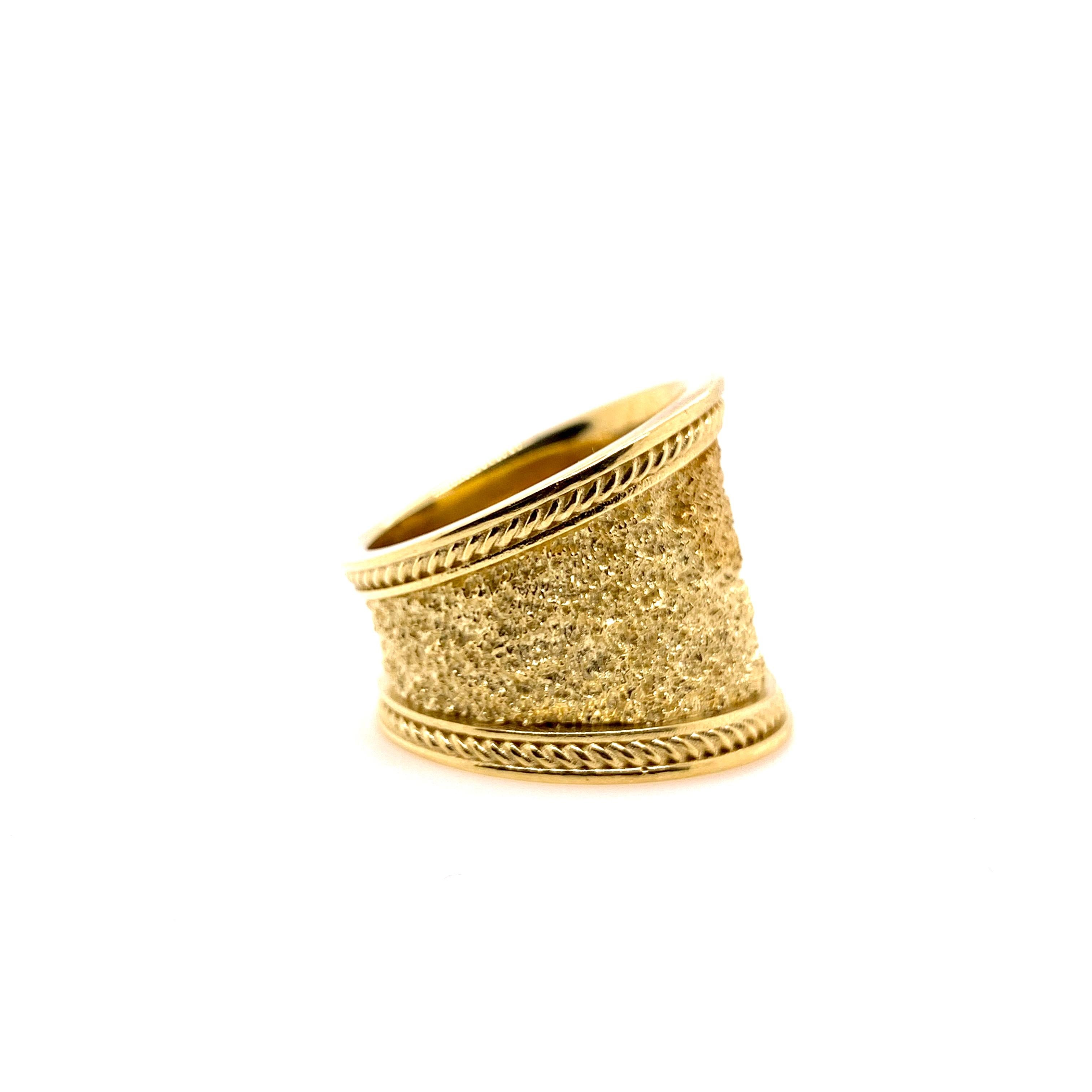 A beautiful textured 18k yellow gold cigar band perfect to be worn casually or formally.  The twisted rope texture on the edges provides a beautiful contrast to the textured center in this yellow gold ring.  The inside is a high shine finish with a