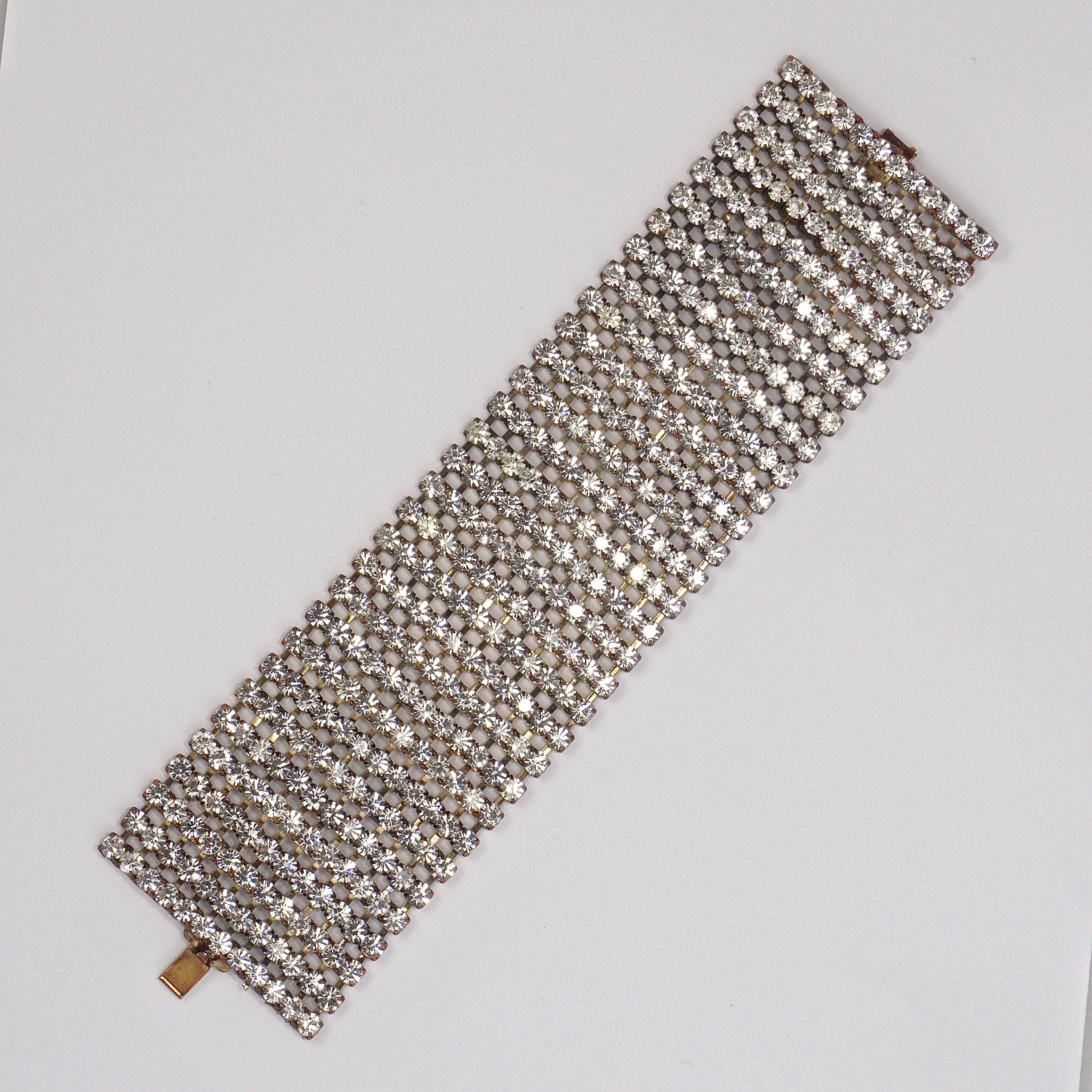 Wide copper tone bracelet, featuring twelve rows of sparkling clear faceted rhinestones. Measuring length 19.3cm / 7.6 inches by width is 5.08cm / 2 inches. Circa 1950s.

This is a beautiful and glamorous vintage statement bracelet for a special