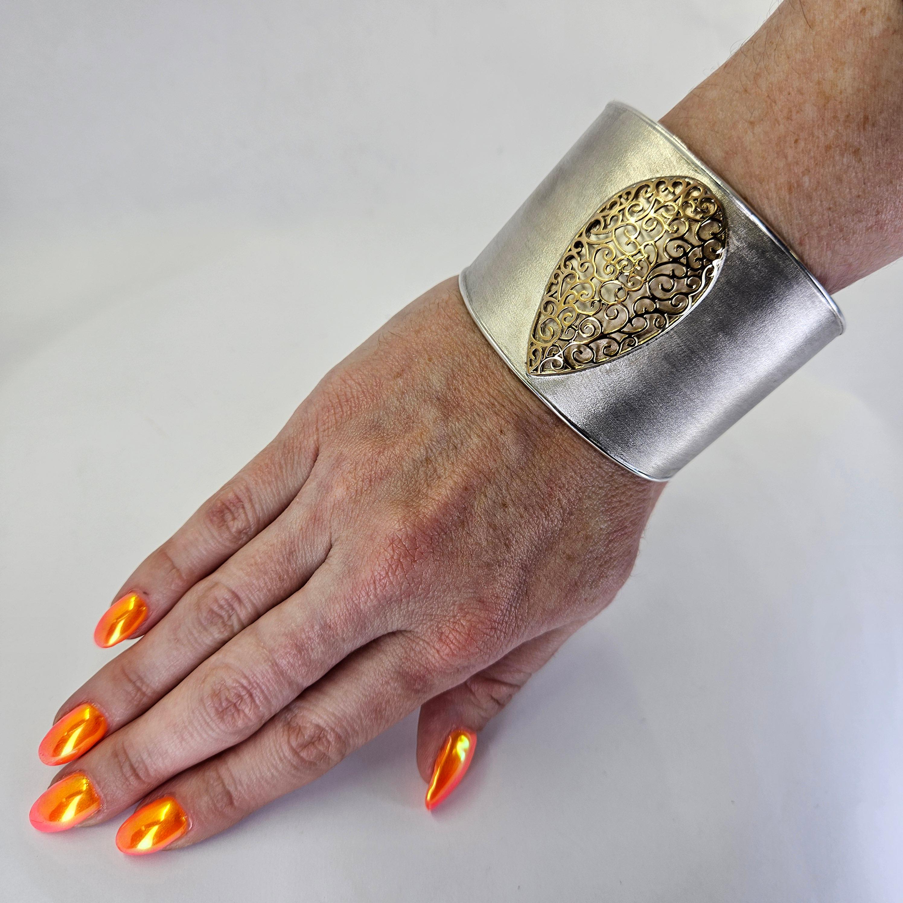 Bracciale largo in argento sterling e oro giallo 14 carati con design a forma di pera e texture spazzolata al centro.  Vestibilità regolabile con affusolamento sul retro. Il peso finito è di 64,6 grammi.

È disponibile anche un bracciale simile con