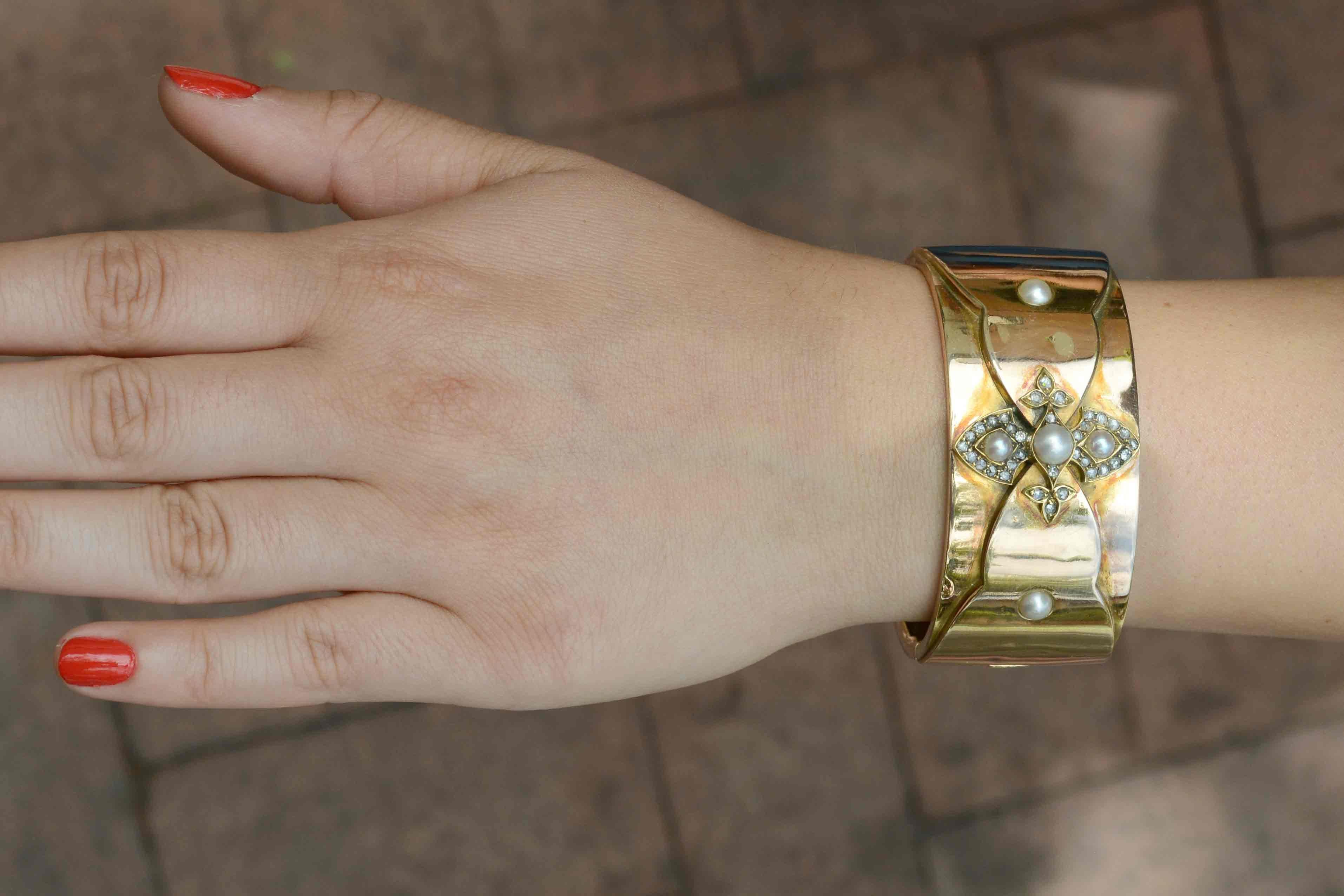 A stunning Victorian pearl and diamond bangle bracelet. This vintage, antique wide cuff displays a strong yet elegant presence on your wrist. Decorated with a cross-like fleur des lis configuration adorned with bright, lustrous pearls and alluring