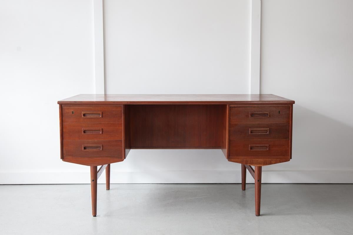 A roomy executive desk from Denmark in teak with six drawers at the front and three open compartments to the rear to store books. Simple and classically mid century in design with a lovely elegance in its clean lines. Professionally restored and in