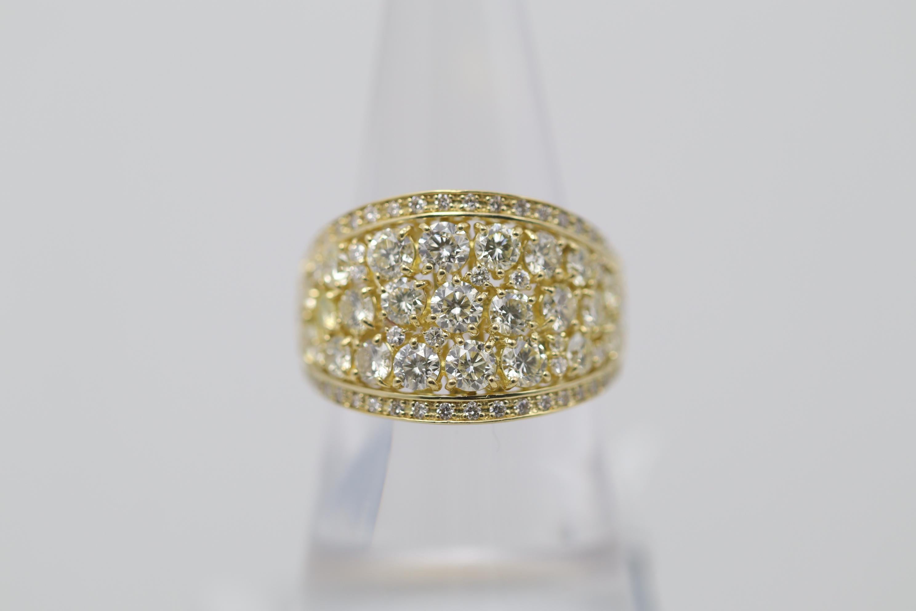 A lovely band ring featuring 3.00 carats of round brilliant-cut diamonds which are cluster set in the center of the ring. Two rows of smaller diamonds are set above and below the cluster for a clean looking finish. Made in 18k yellow gold and ready