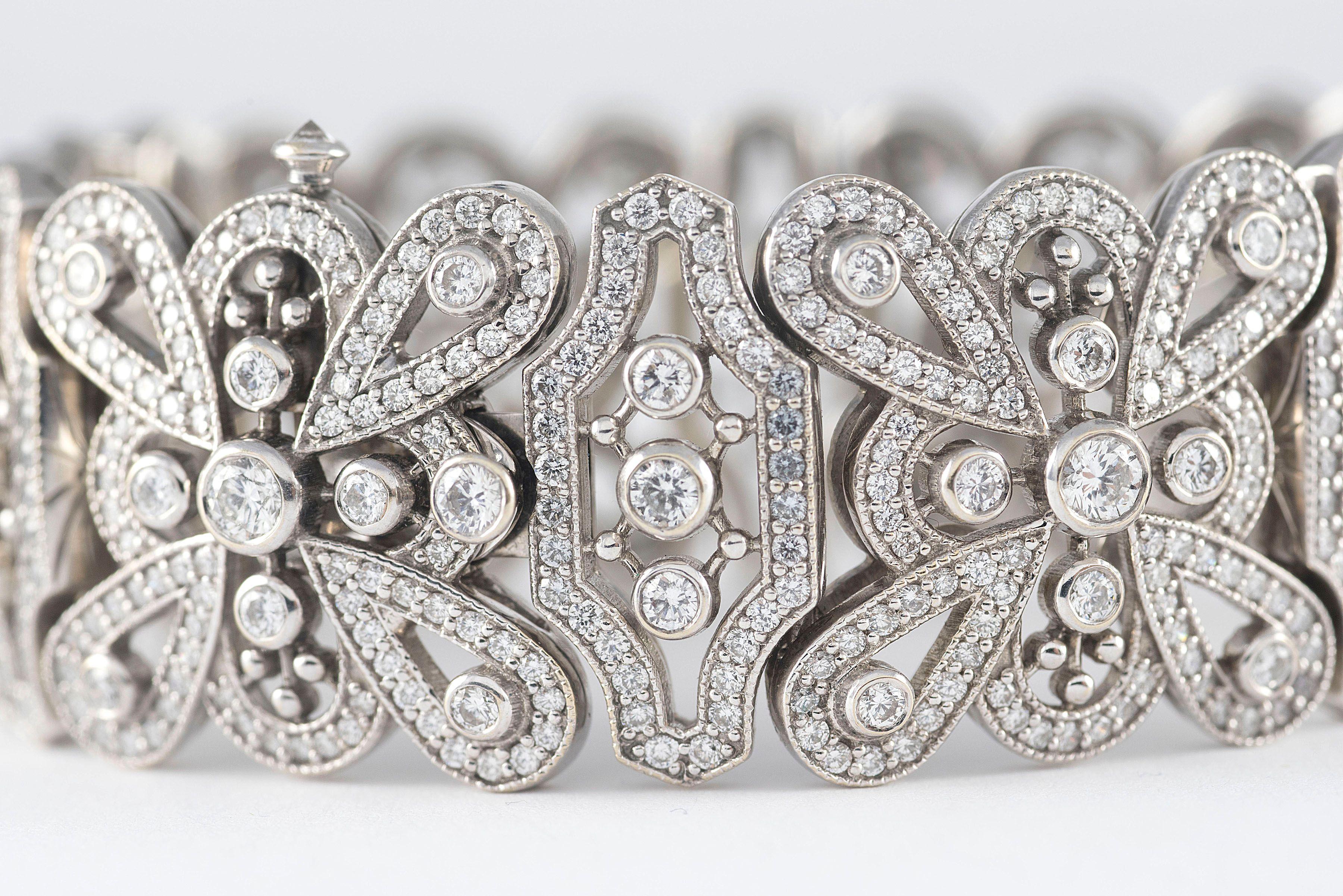 Intricately crafted in 18kt white gold, this exquisite custom made wide link bracelet features 11.28 carats of round diamonds, F color, VS-VVS clarity arrayed over a fanciful openwork design. 


