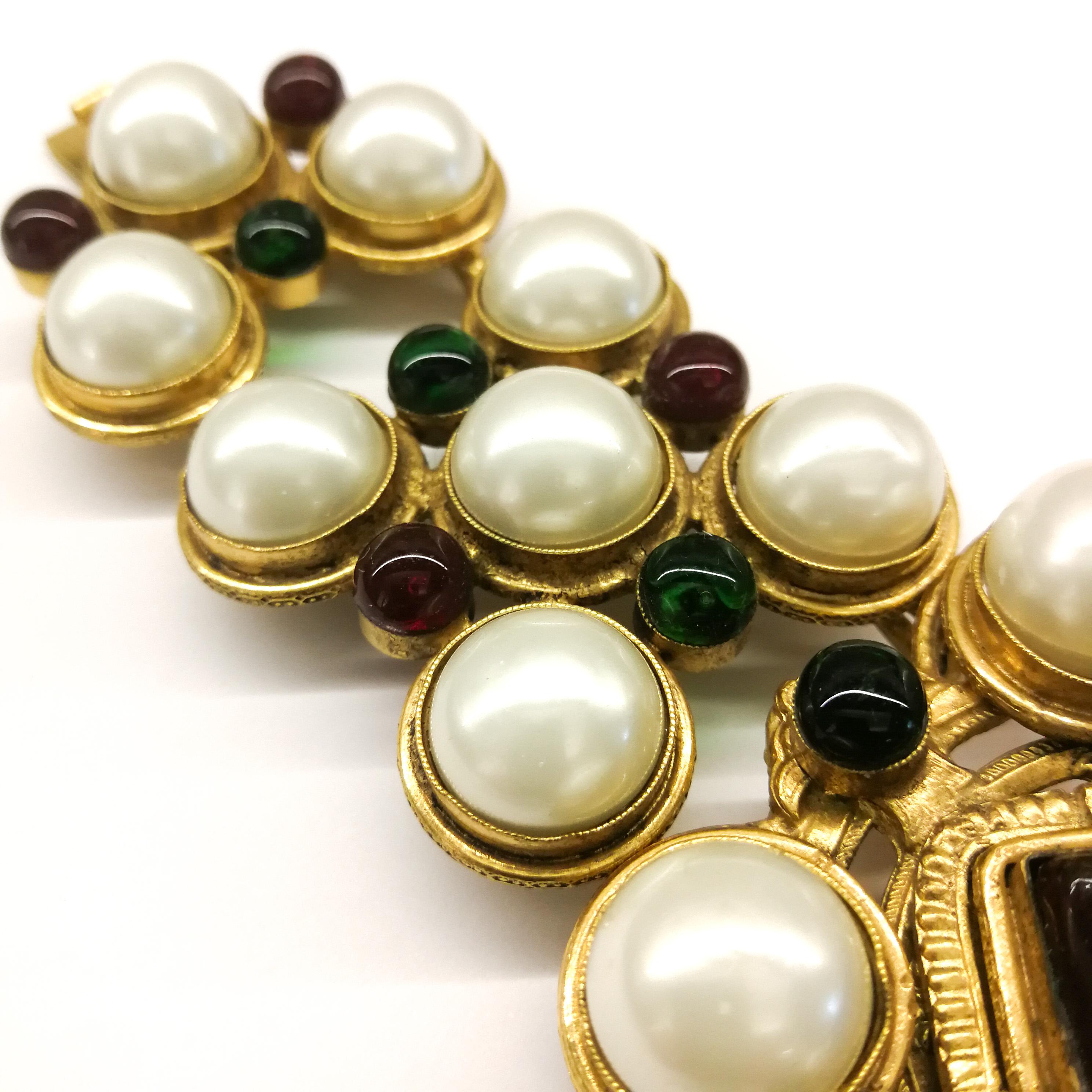 A very strong and dazzling wide bracelet by Maison Goossens for Chanel, set with lush pearl cabuchons and emerald and ruby poured glass, with a large square ruby/cornelian  poured glass square in the centre, all set in gilded metal. It is