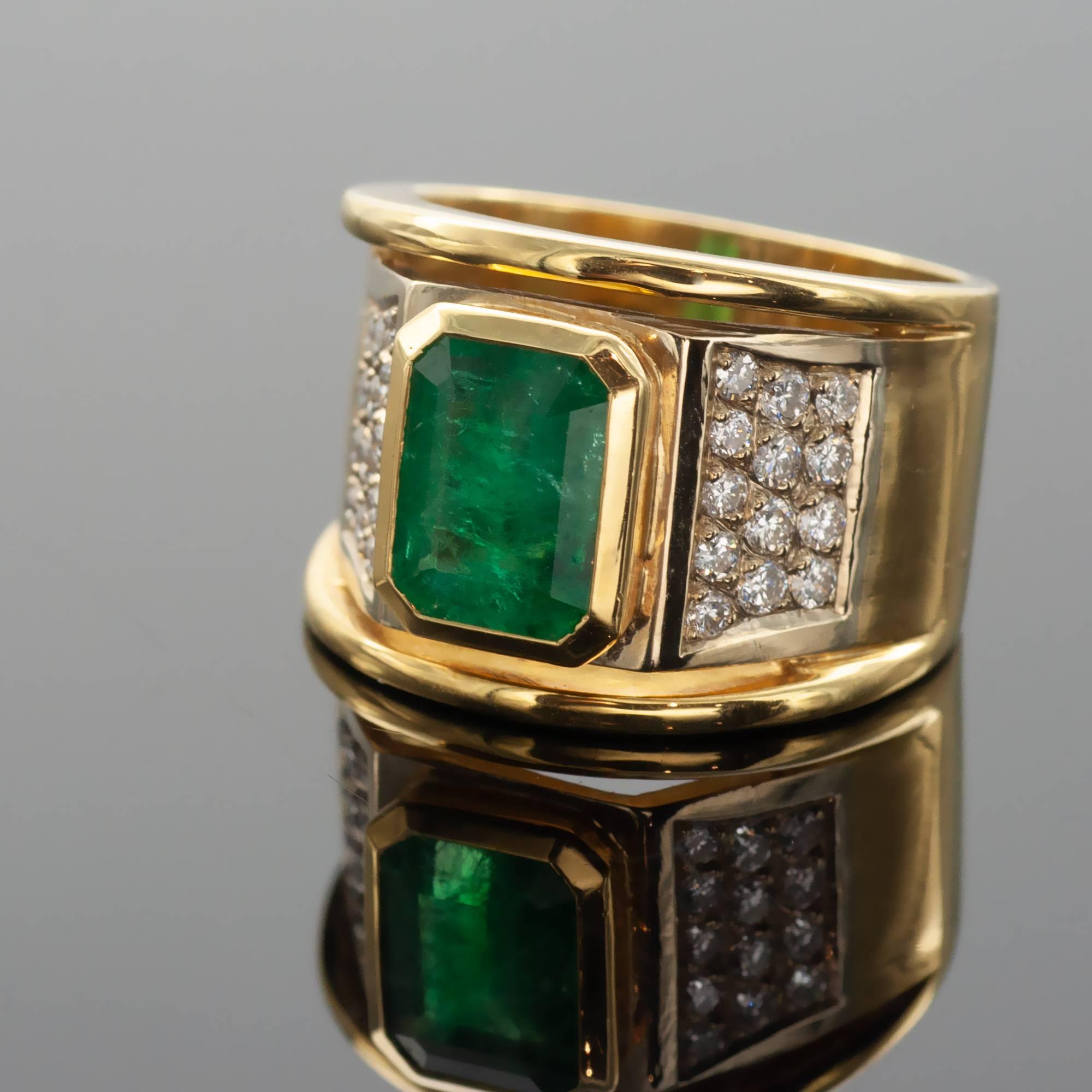 Stylish emerald cocktail ring. The ring itself is a wide 18kt yellow gold band in the center of which a 2.24 carat emerald is bezel set . 26 round diamonds ( ±0.52 carat) set on white gold on both sides of the emerald enlighten the whole ring.