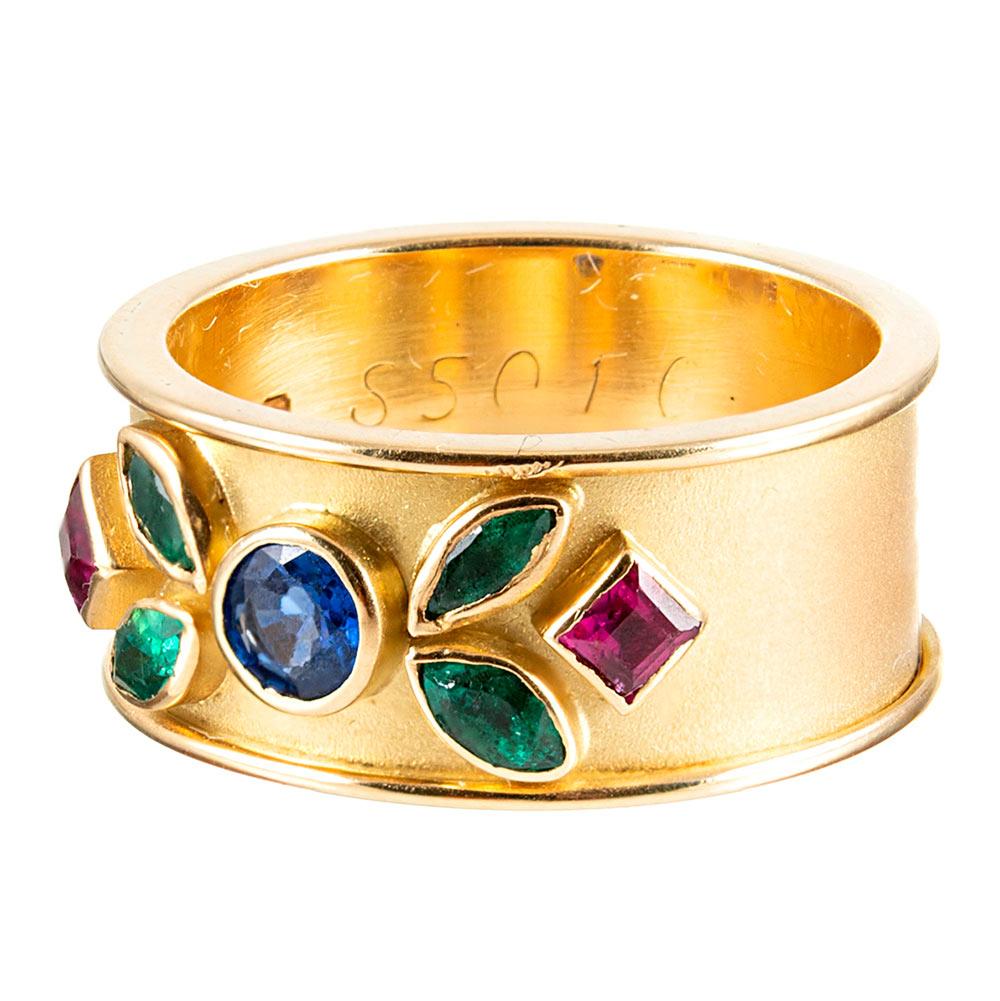 A beautifully-conceived piece, made of 18 karat yellow gold and set with an artful display of colorful gemstones. The substantial body of the band is satin-finished, with high-polished edges and high-polished bezels for the round- marquis- and