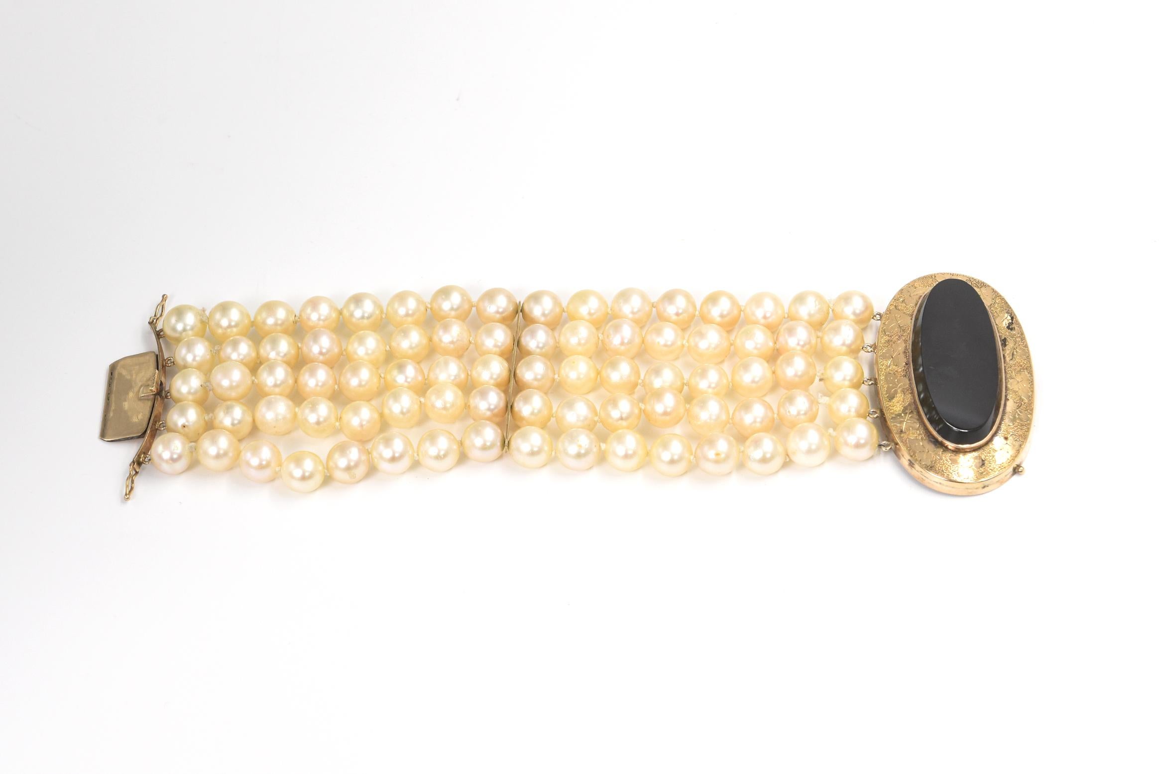 Elegant five strand cultured pearl bracelet with a Victorian clasp.  The clasp features a beveled onyx center in an etched leaf 14k yellow gold frame. The size of the pearls range 8.25 - 8.50mm.   The pearls have blemishes.

The clasp is a push