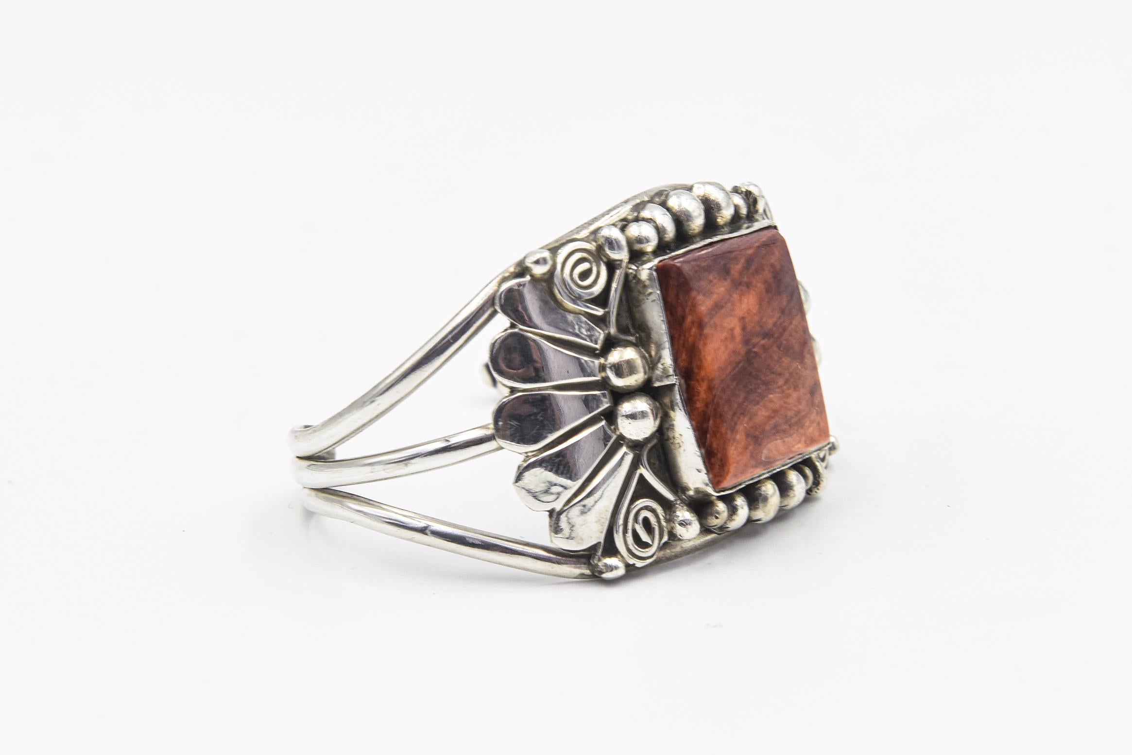 Bracciale Navajo vintage realizzato a mano dall'artista Gilbert Adakai contenente una grande conchiglia di ostrica spinosa di forma quadrata incastonata in un castone martellato a mano.  Si trova all'interno di un bracciale d'argento decorato con