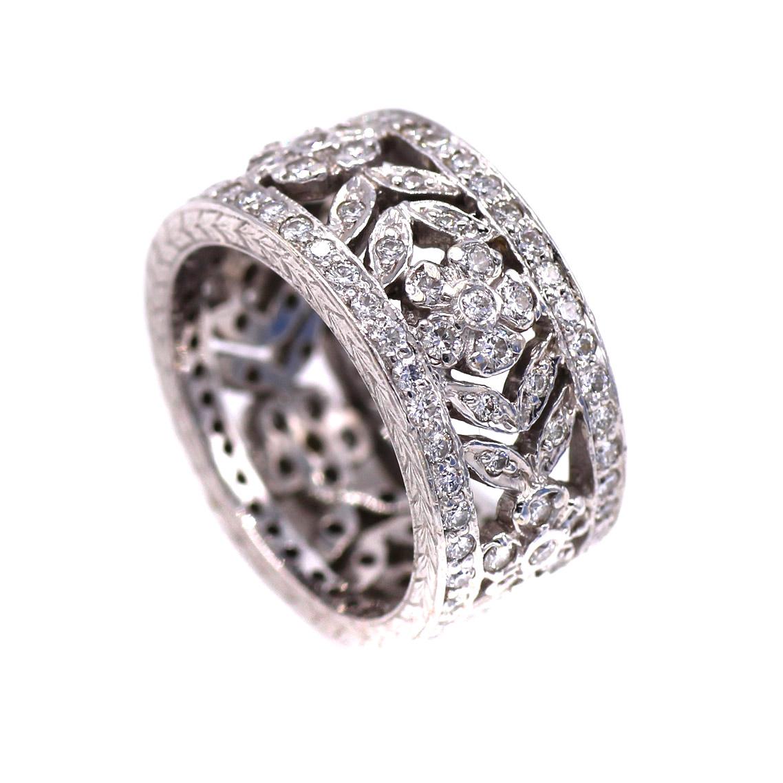 Beautifully designed and masterfully handcrafted this unique 1950s eternity band exhibits an amazing craftsmanship. Between two outer bands with channel set bright white round diamonds, a floral design of blossoms and leaves repeats its self around