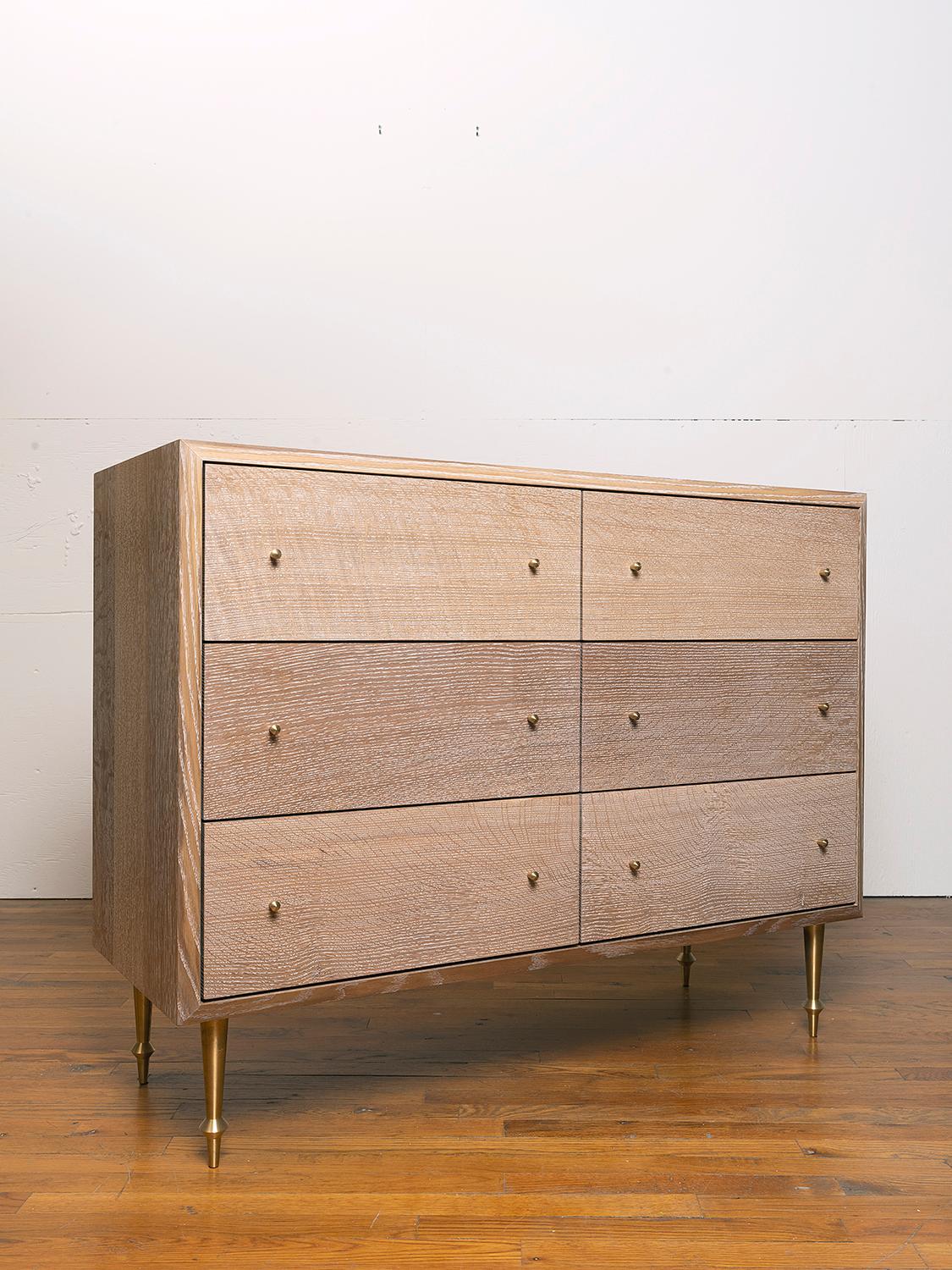 Solid white oak with turned brass legs and drawer pulls.
Cerused finish.
Dimensions: 46” W x 18” D x 36” H.
 