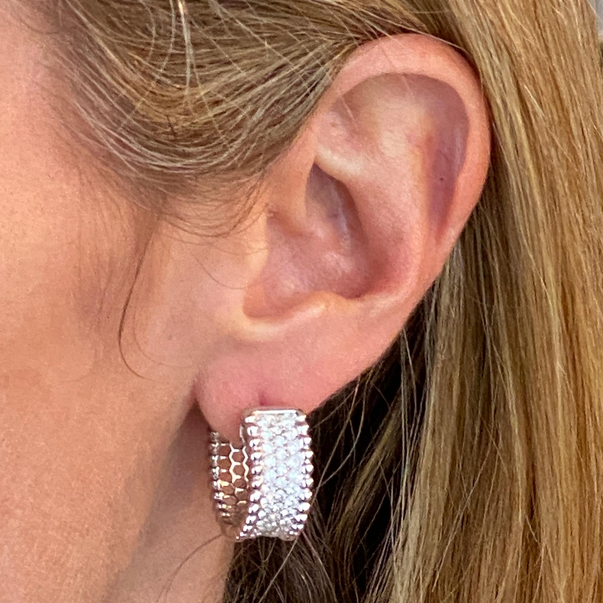 Stylish wide diamond hoop earrings fashioned in 18 karat white gold. The hoops feature 2.00 carats of round brilliant cut diamonds graded G-H color and SI1 clarity. The earrings measure .75 inches in diameter and .40 inches in width. Weight: 17.6