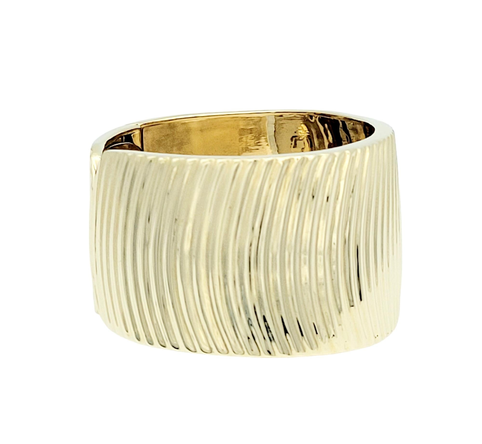 This wide cuff bracelet, crafted in 14 karat yellow gold, is a statement of bold elegance and modern sophistication. The presence of ridges on the bracelet adds texture and visual interest, creating a dynamic and stylish look. The inclusion of a